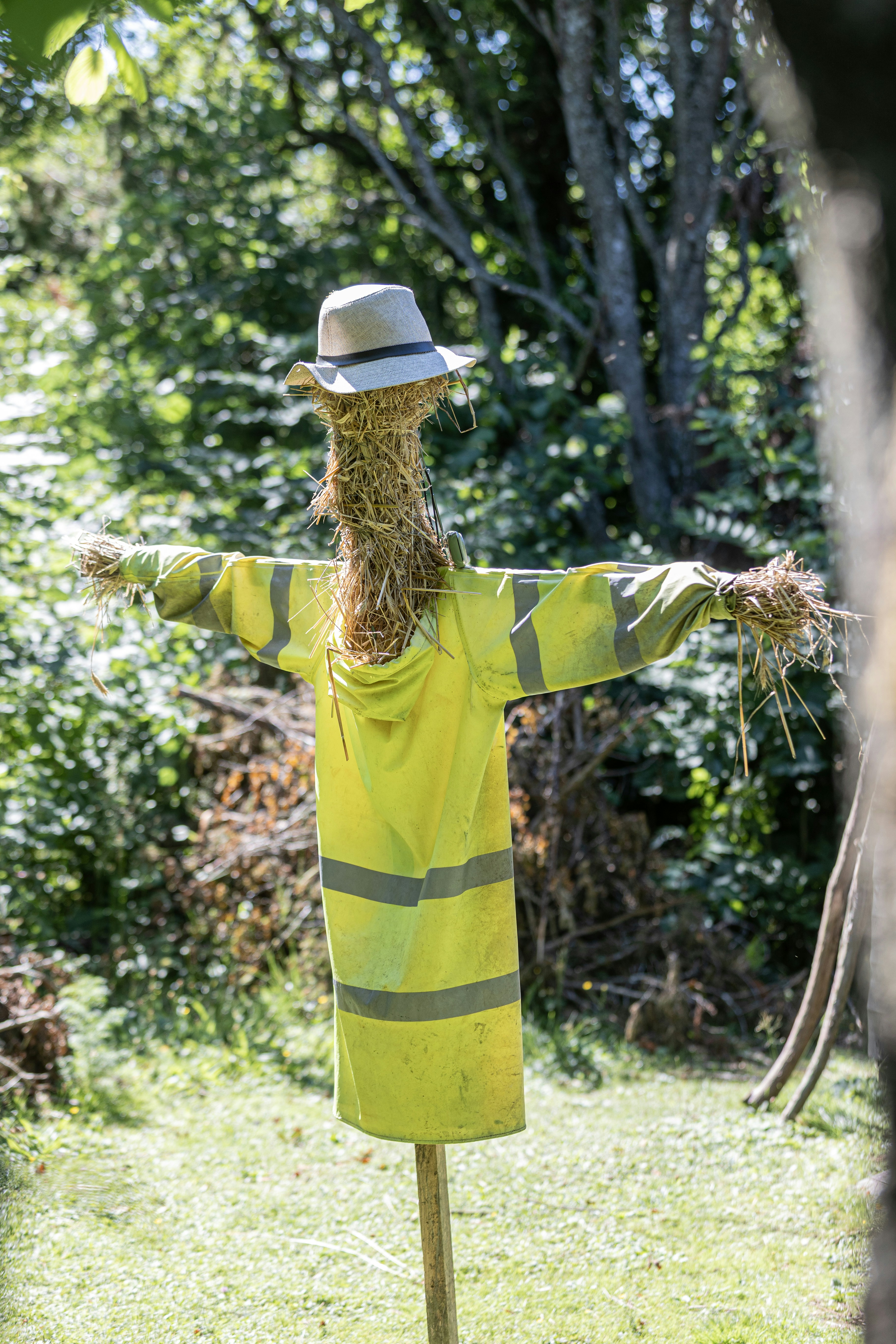 Un espantapájaros con chaqueta reflectante amarilla y sombrero al aire libre.