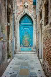 Old blue arched door at end of narrow stone alley