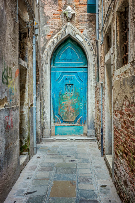 Old blue arched door at end of narrow stone alley