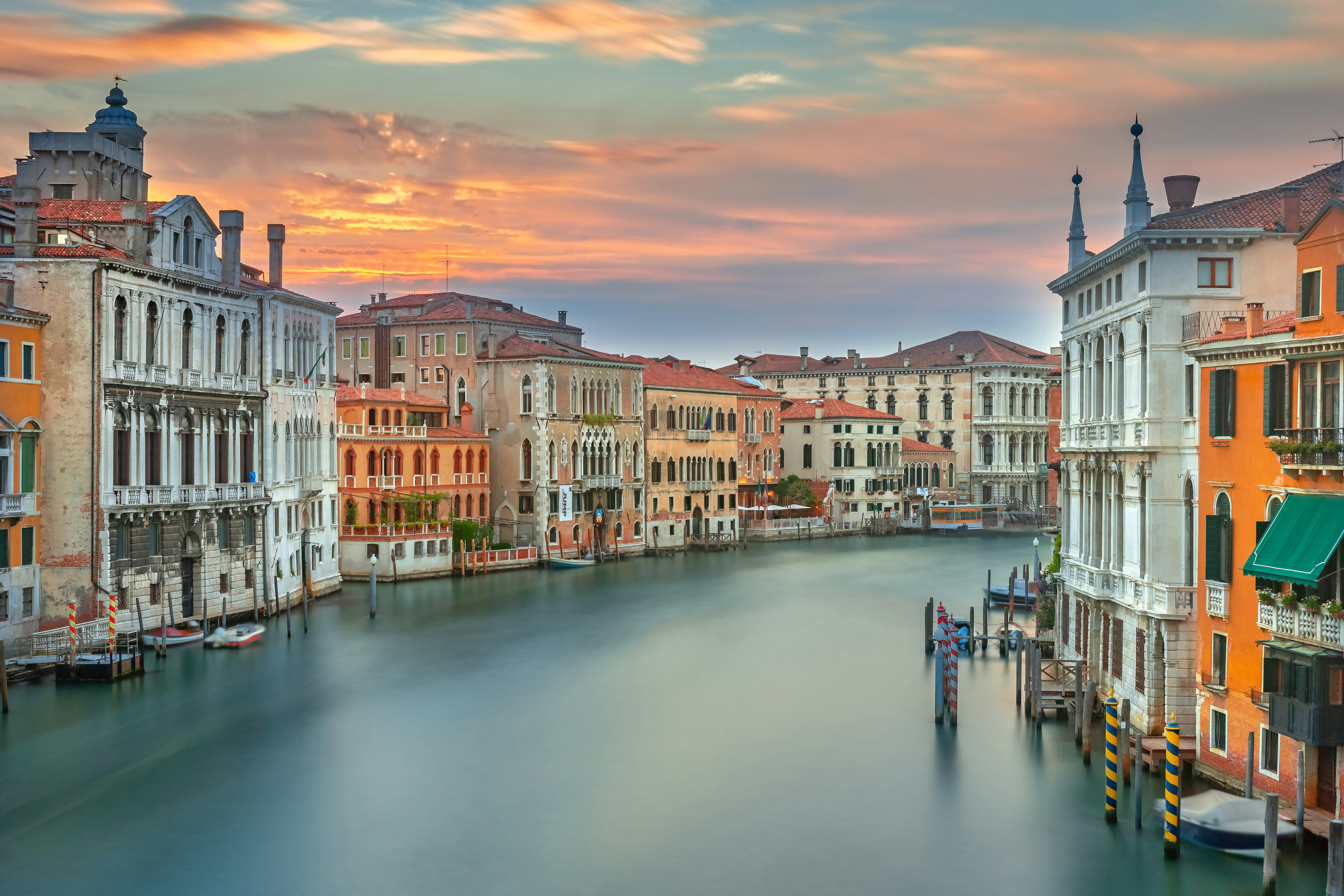 Historic venetian buildings line the grand canal at sunset.