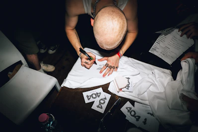 A person signs a white t-shirt with a marker.