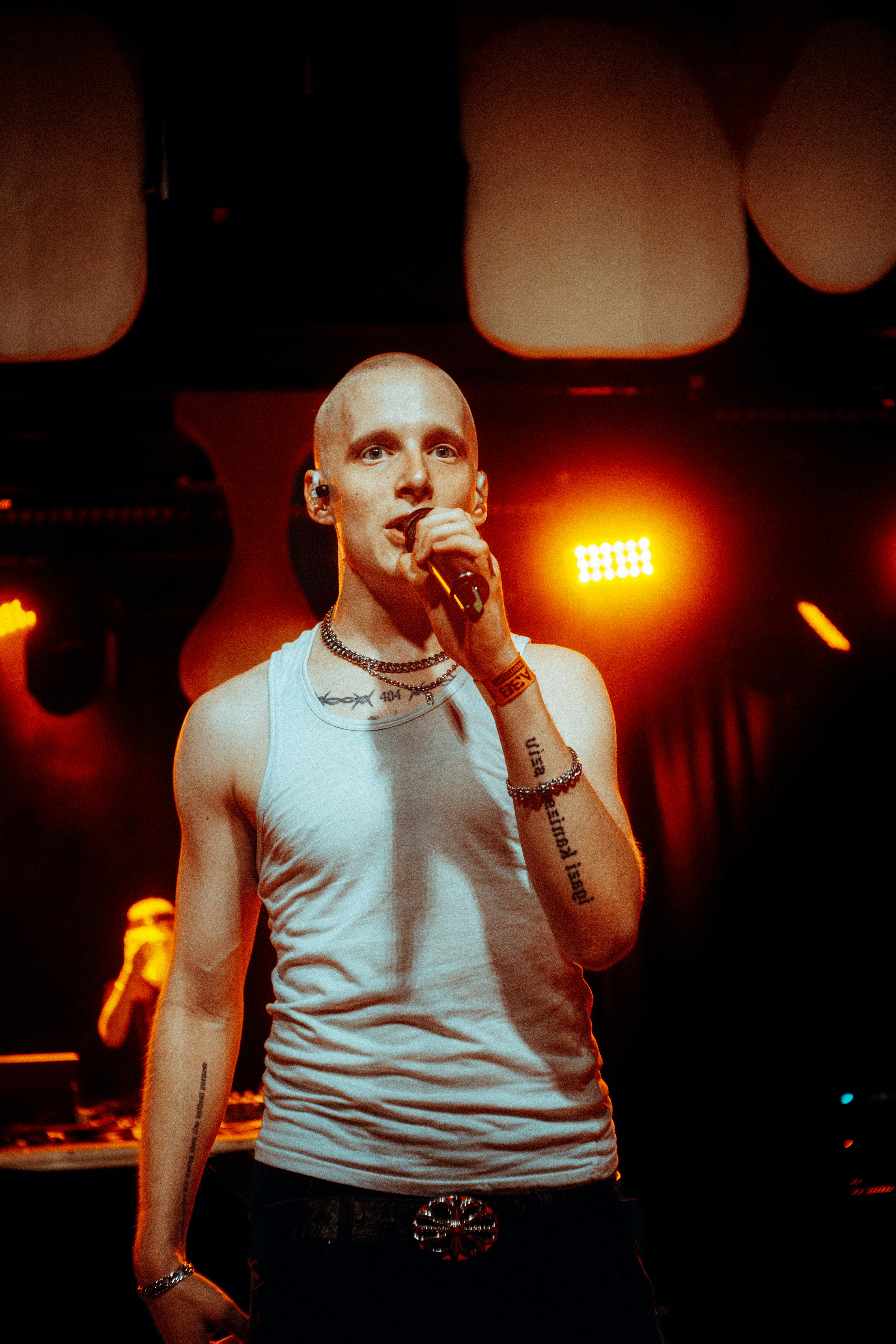 A bald man sings into a microphone on a stage