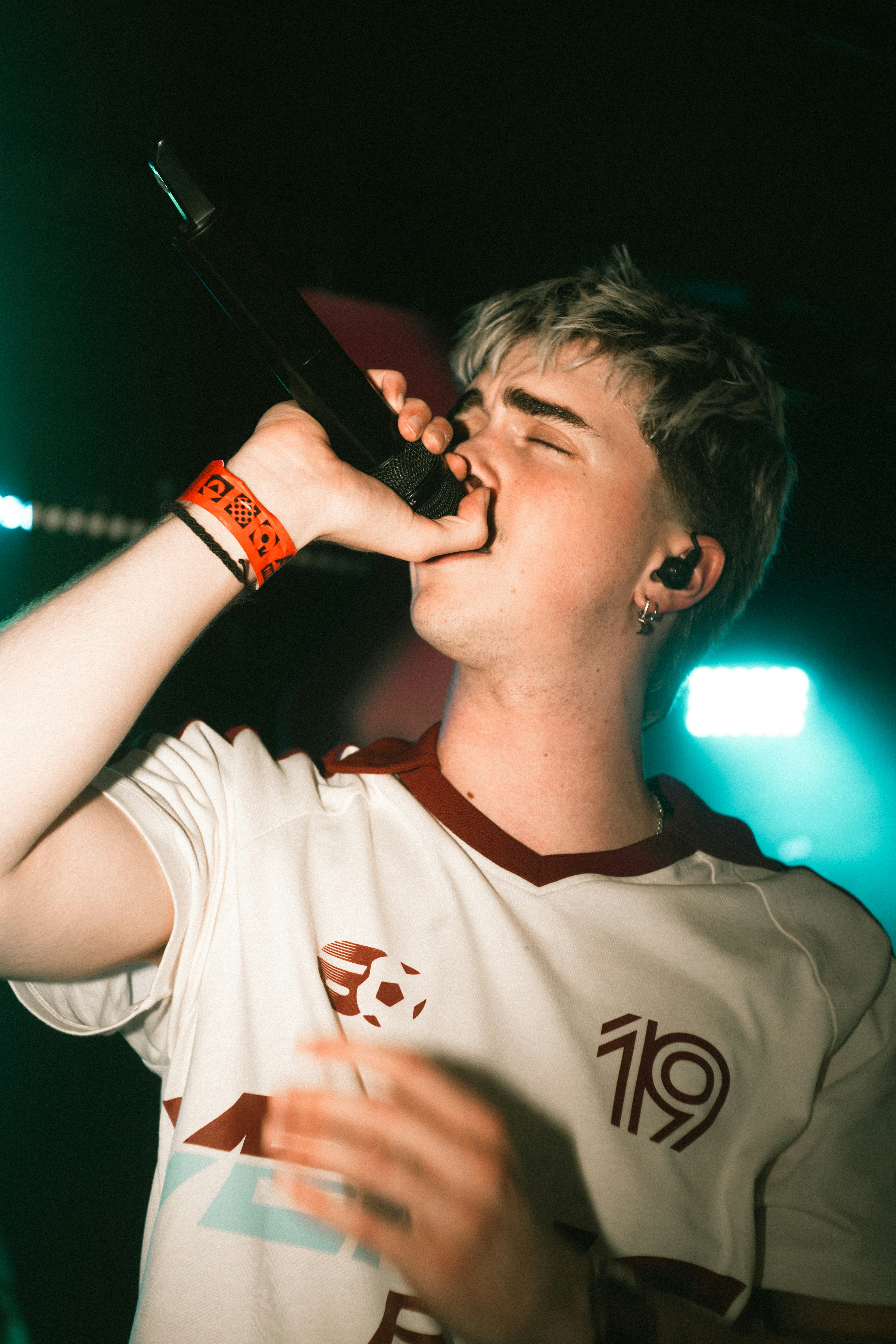 Young man with blonde hair singing into a microphone