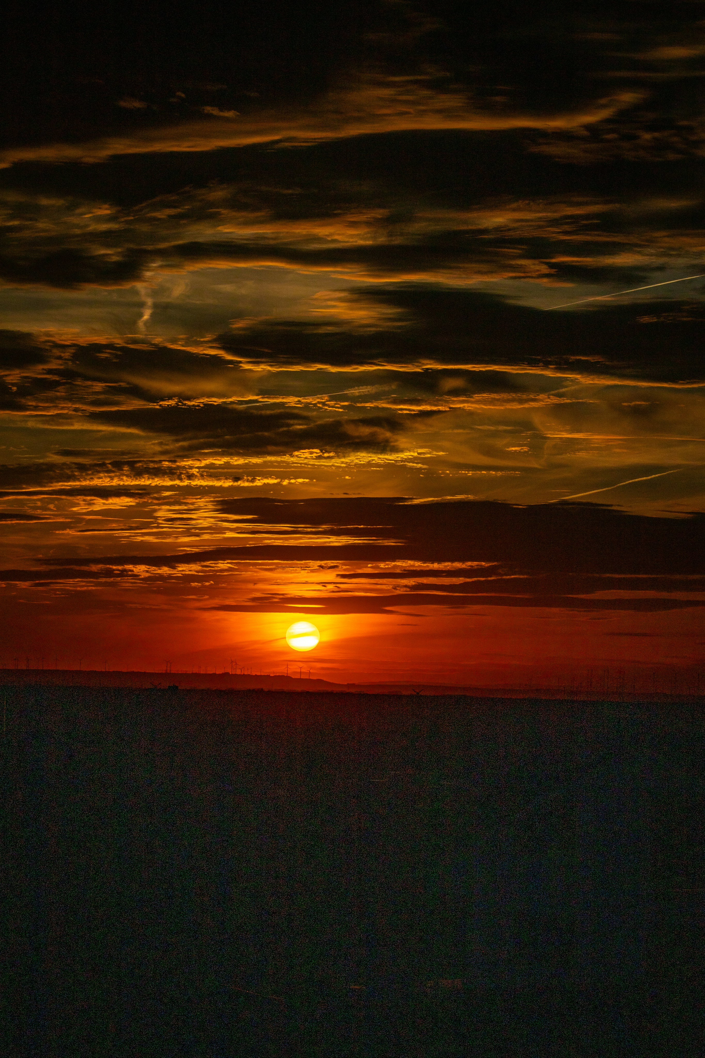 A dramatic sunset with dark clouds over a vast horizon.