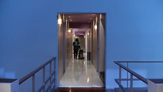 A person cleans a long, modern hotel hallway.