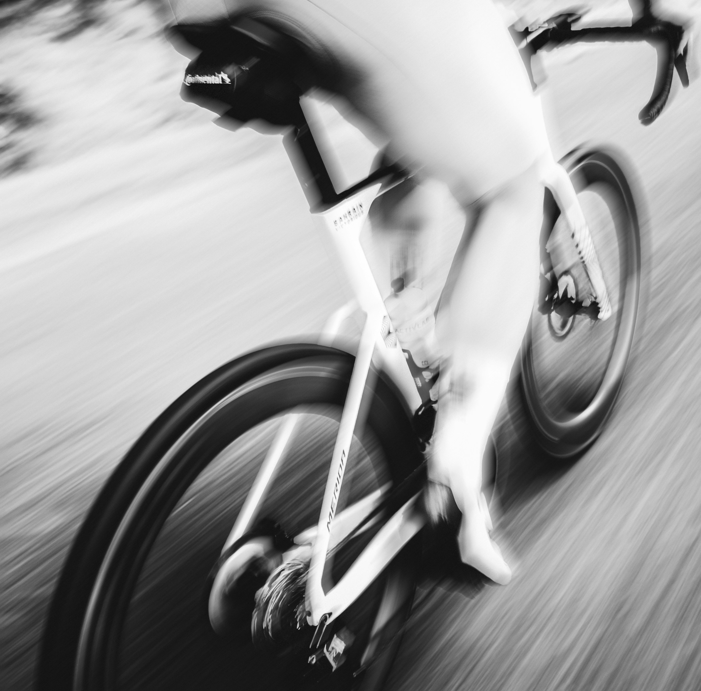 A person cycling fast on a road with motion blur.