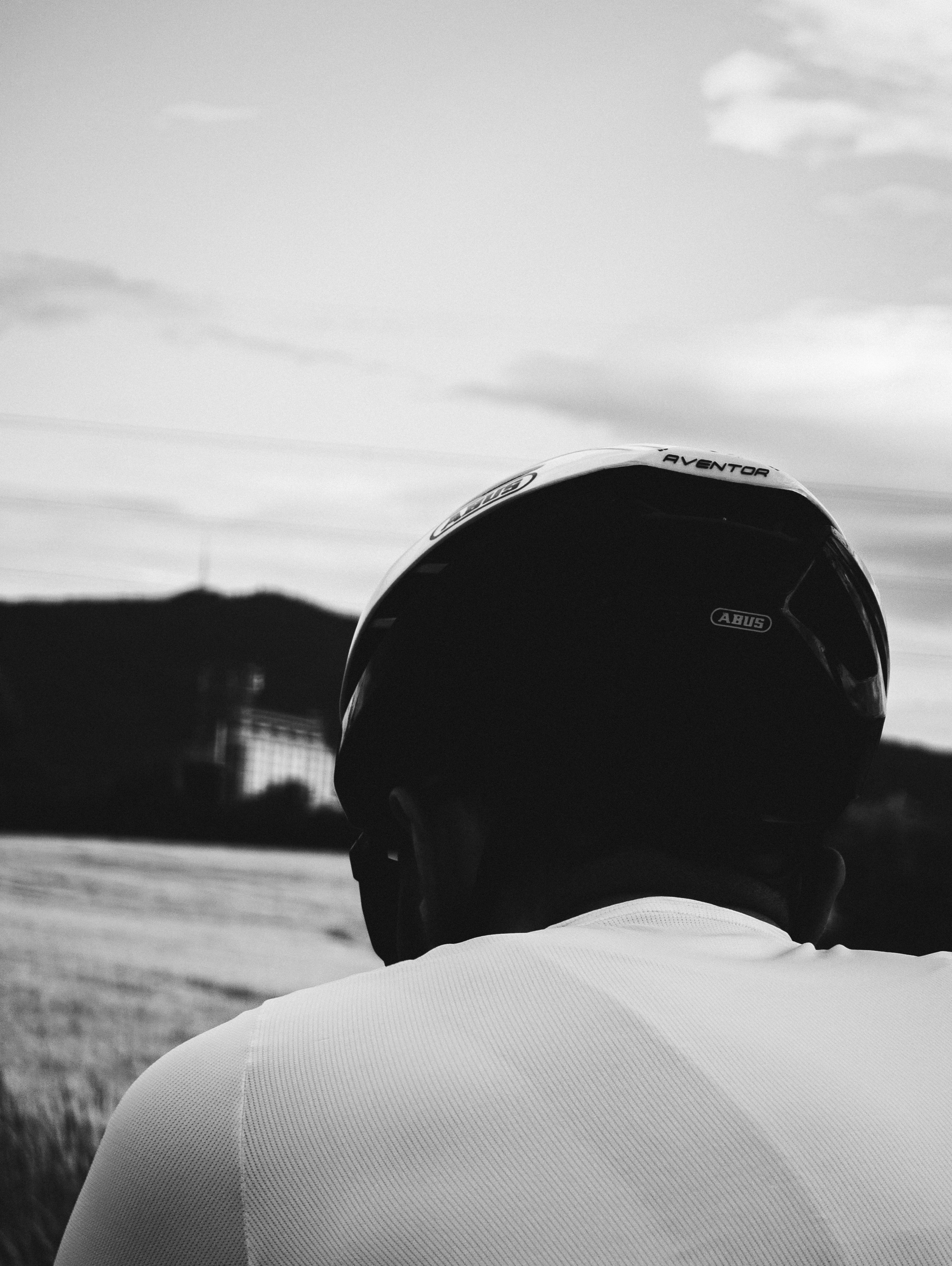 Cyclist wearing helmet looking at a monochrome landscape.