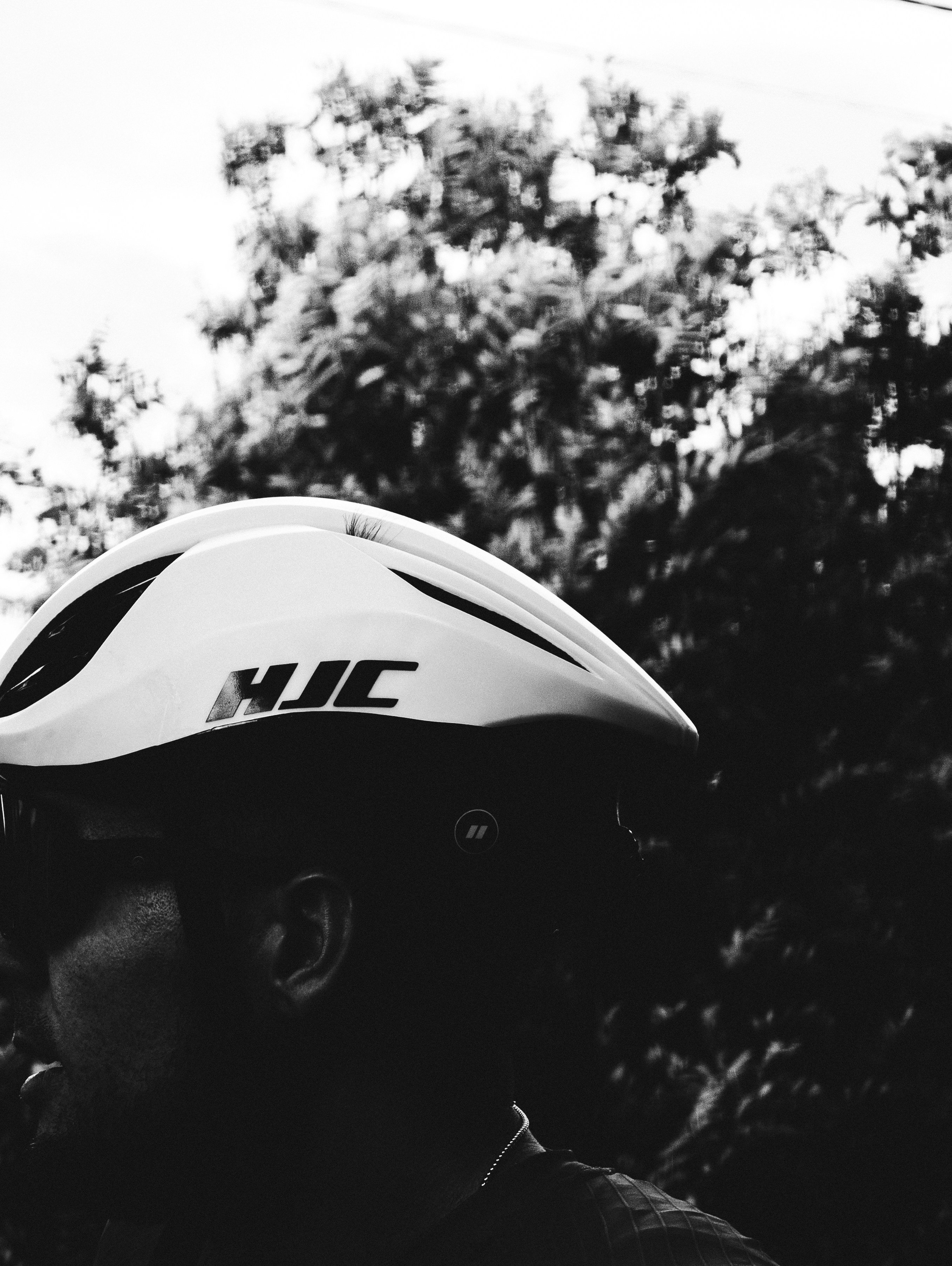 Person in white hjc helmet, silhouetted against trees.