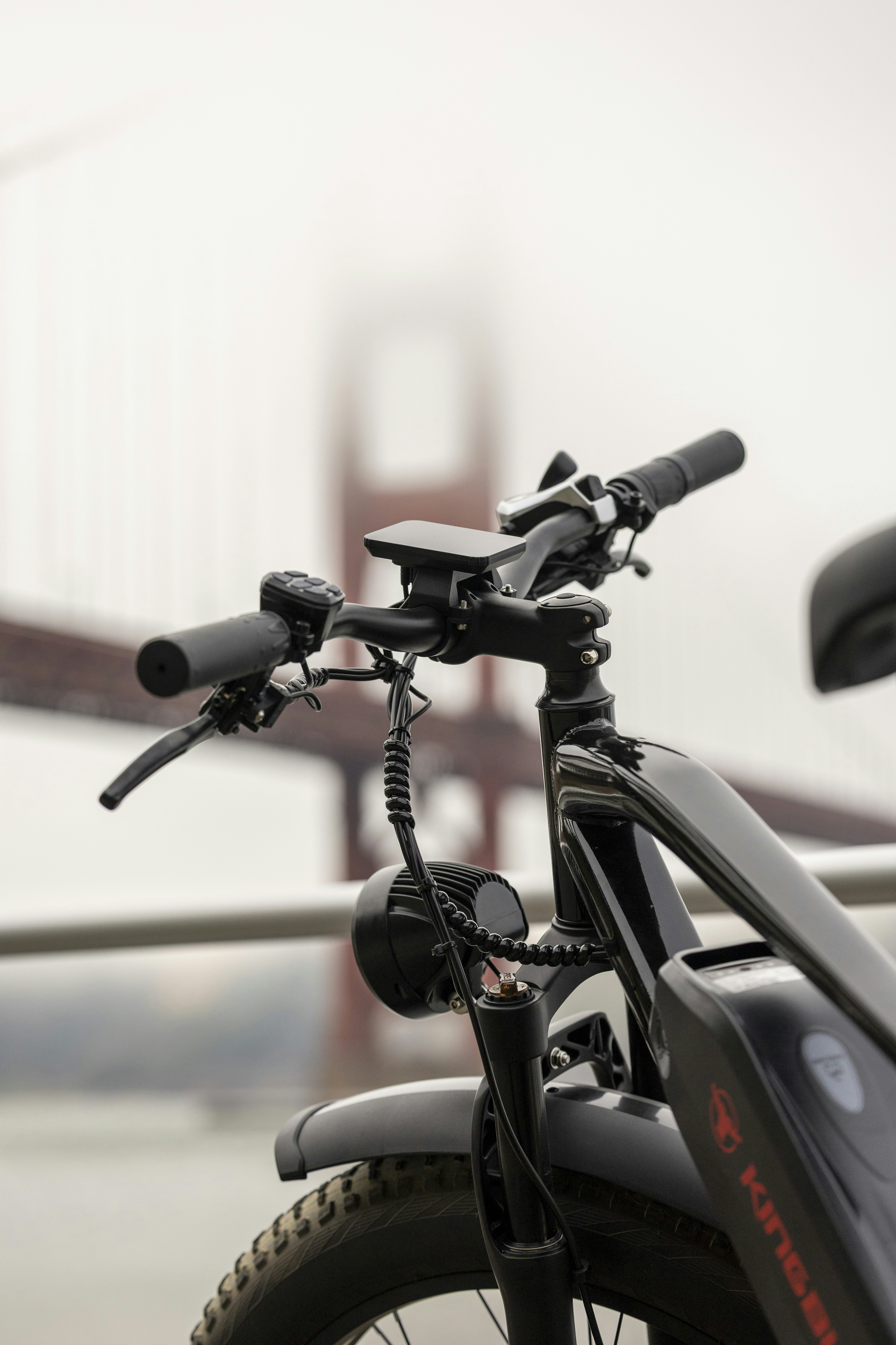 Black electric bike with golden gate bridge in foggy background.