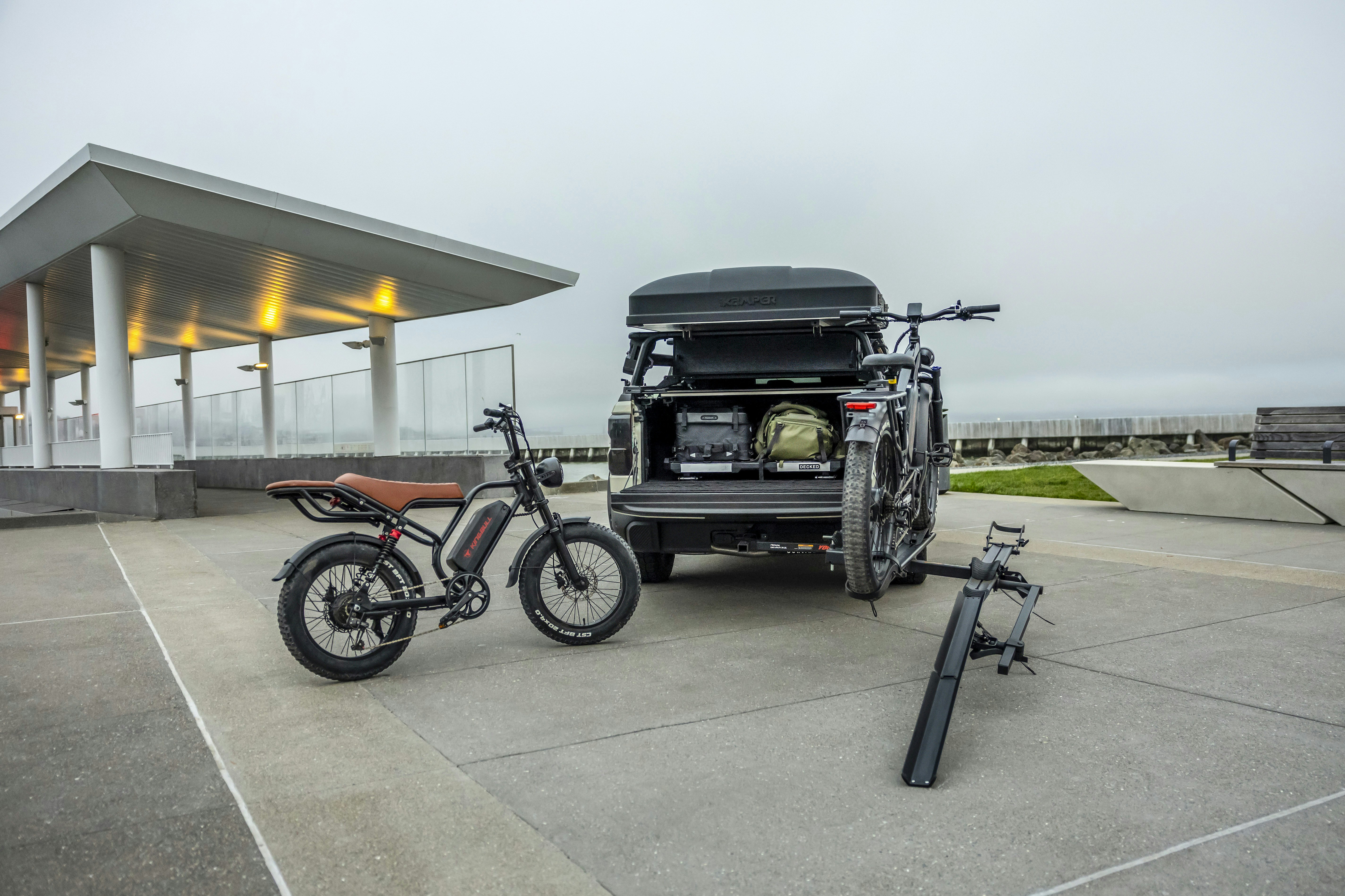 An e-bike and truck with gear parked on concrete.