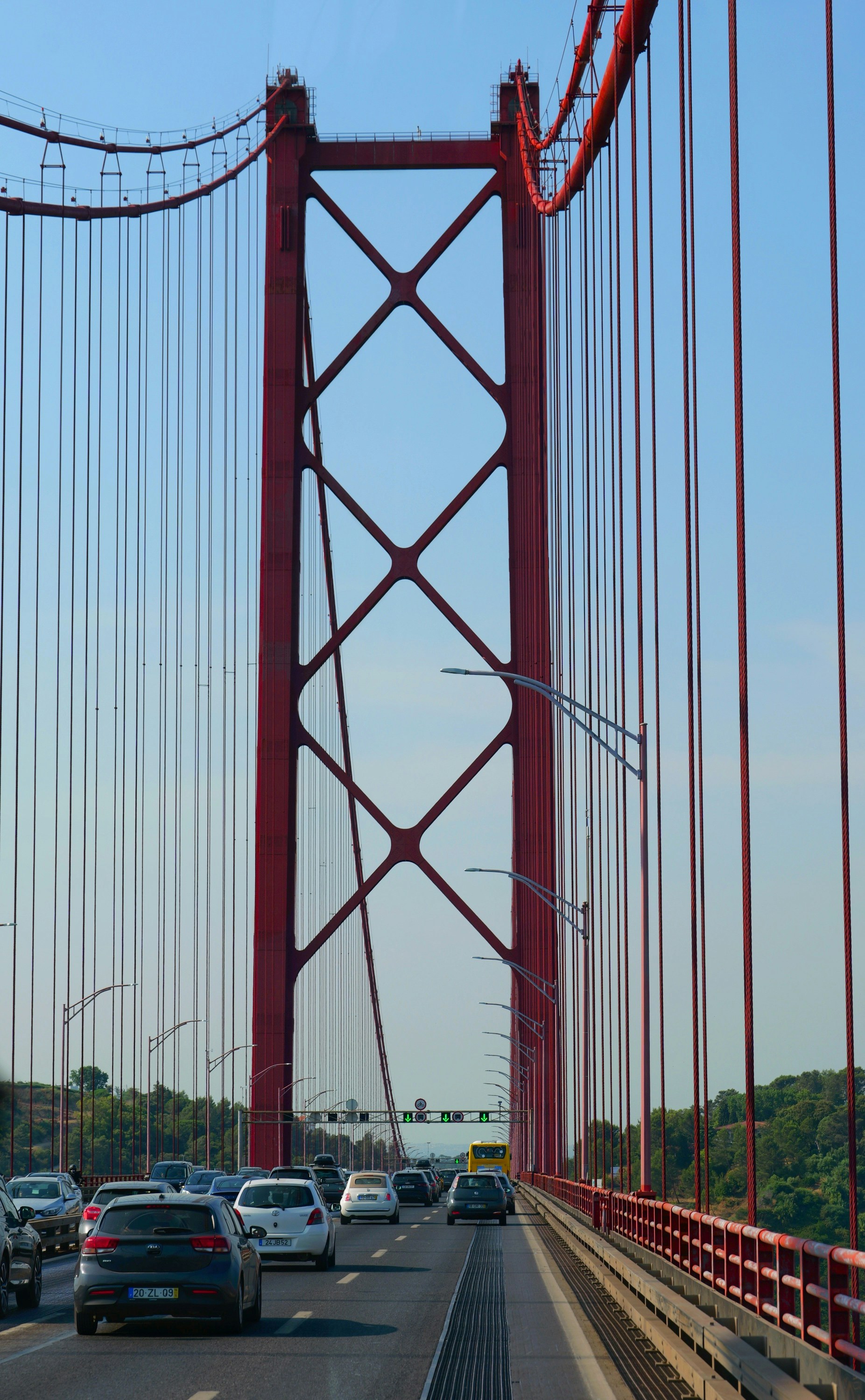 Cars driving across a large red suspension bridge.