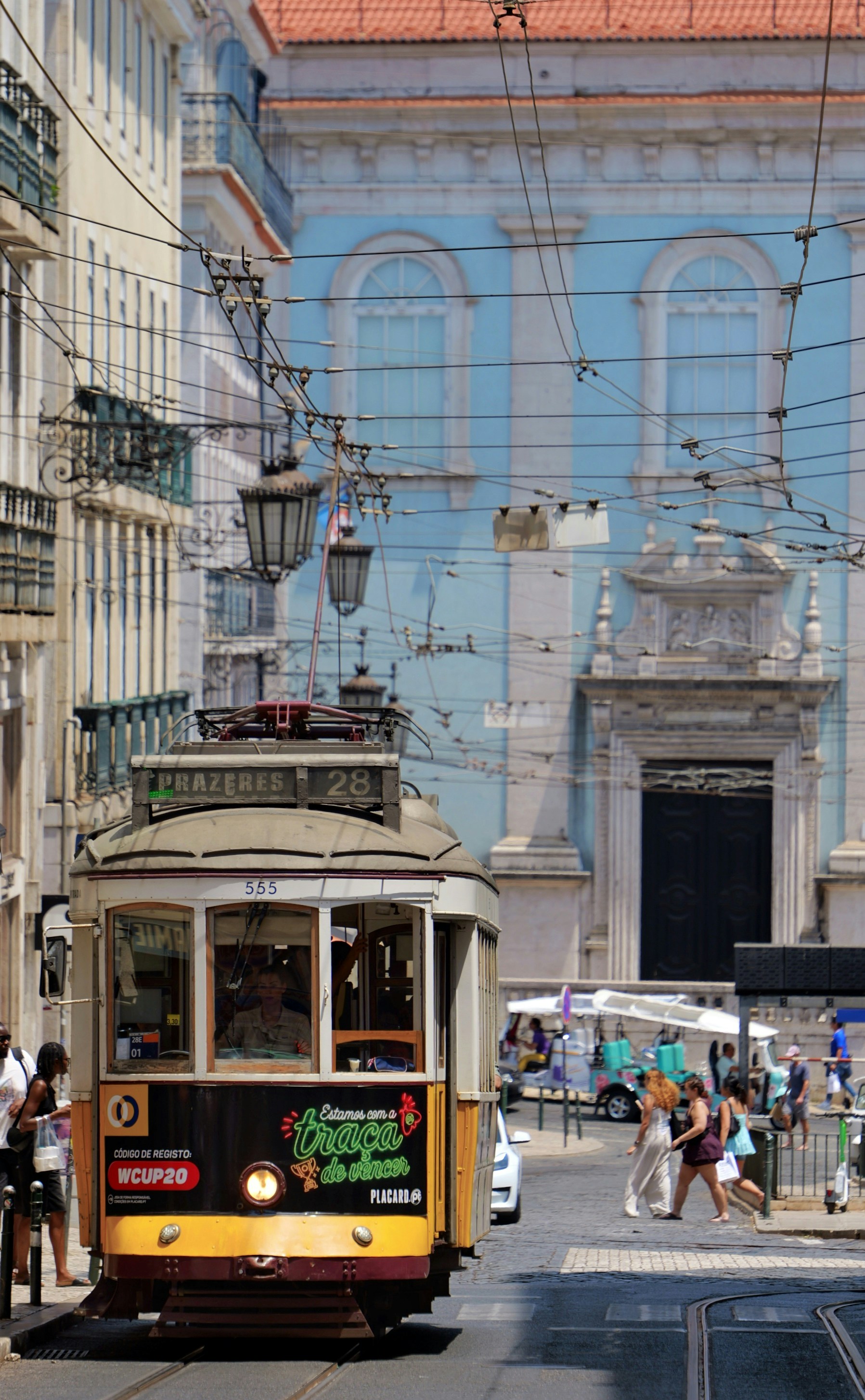 Vintage yellow tram on a city street, blue building background.
