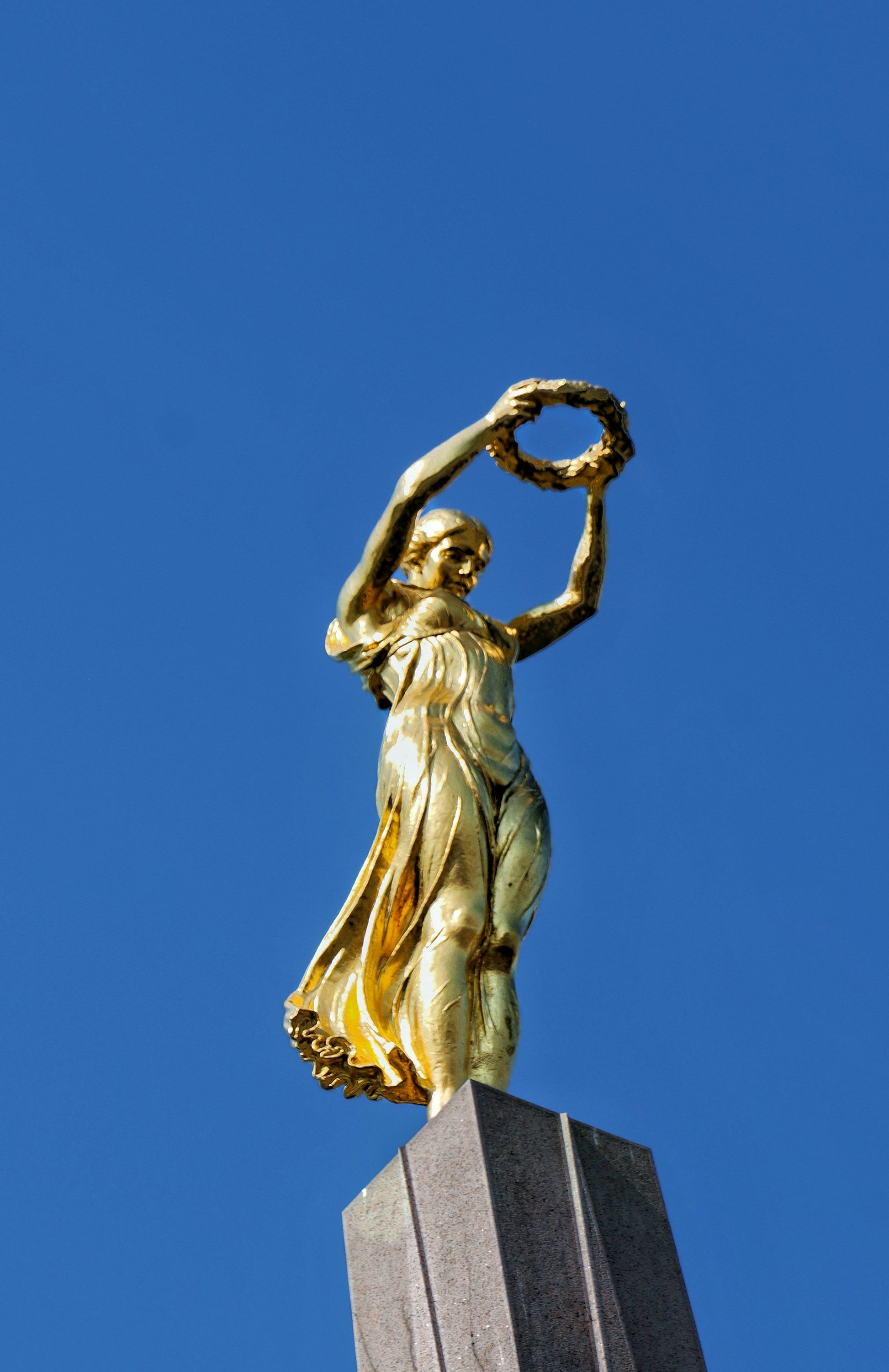 A golden statue of a woman holding a wreath.