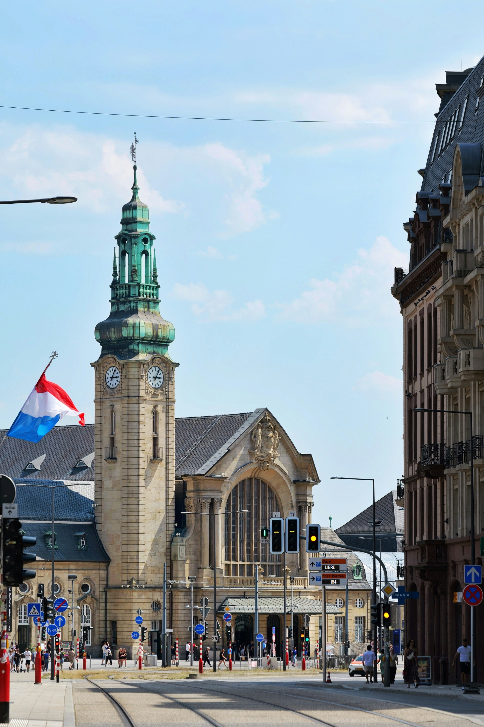 Luxembourg train station with clock tower and flag.