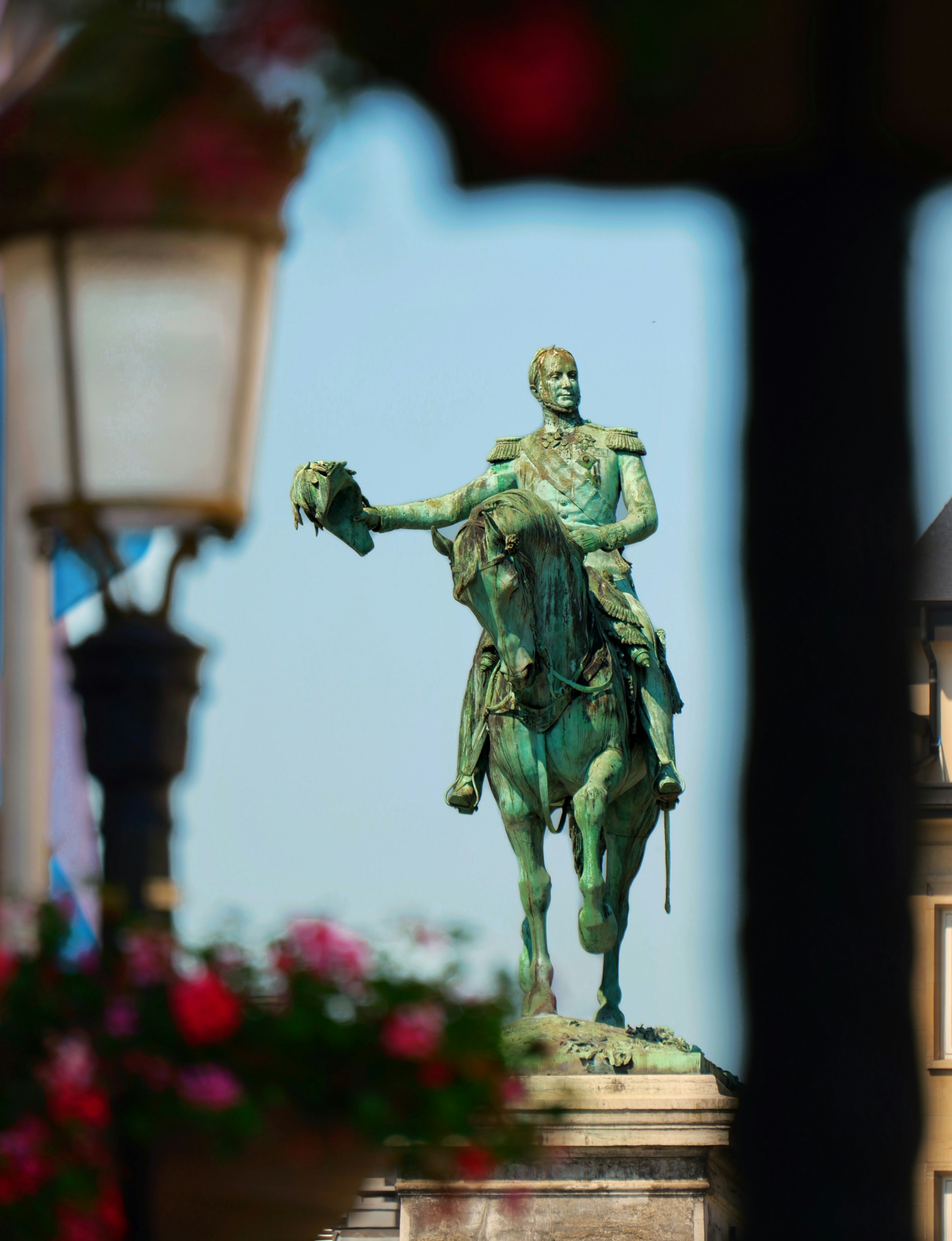 Green equestrian statue of a man against blue sky.