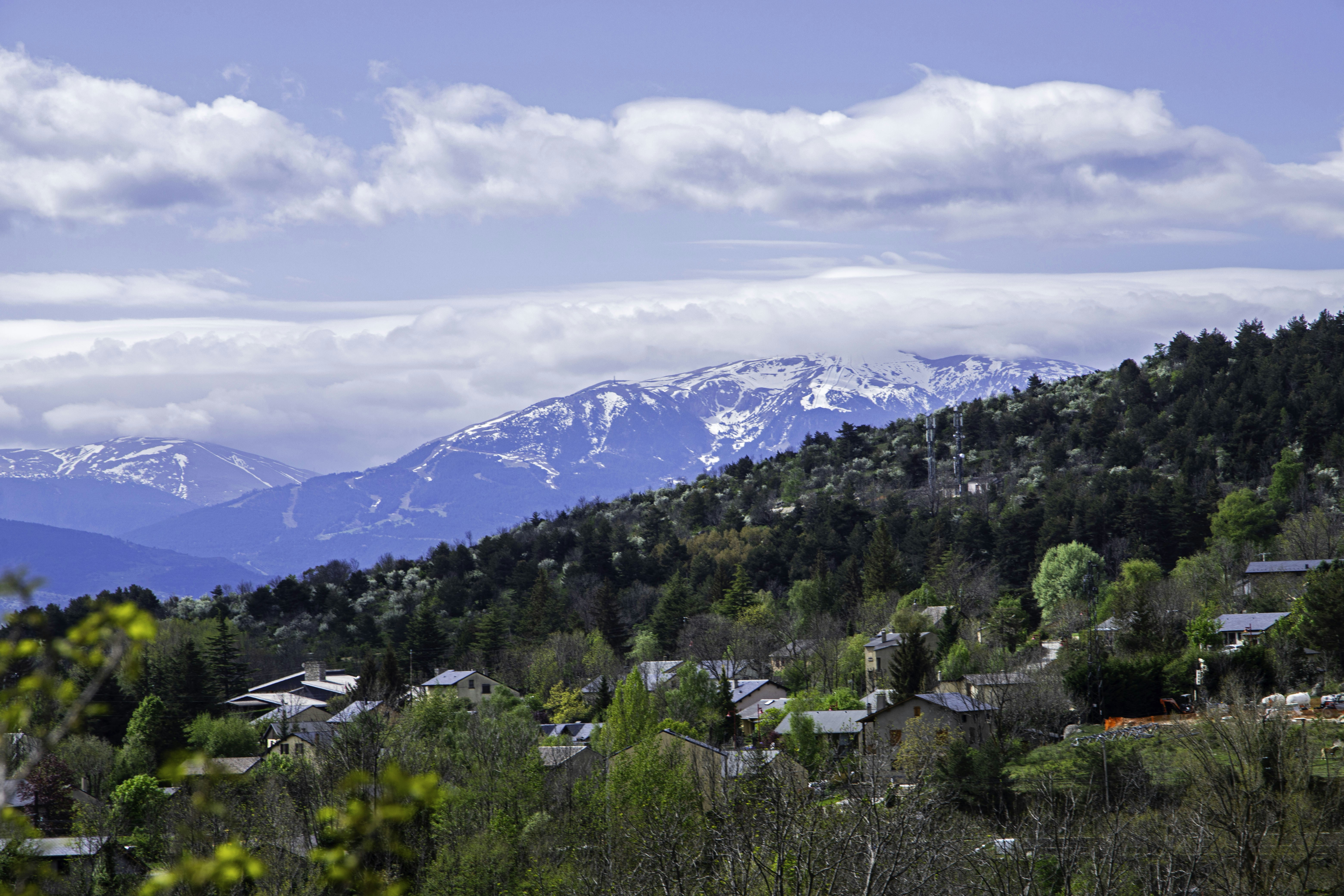 Snow-capped mountains overlook a green village landscape.