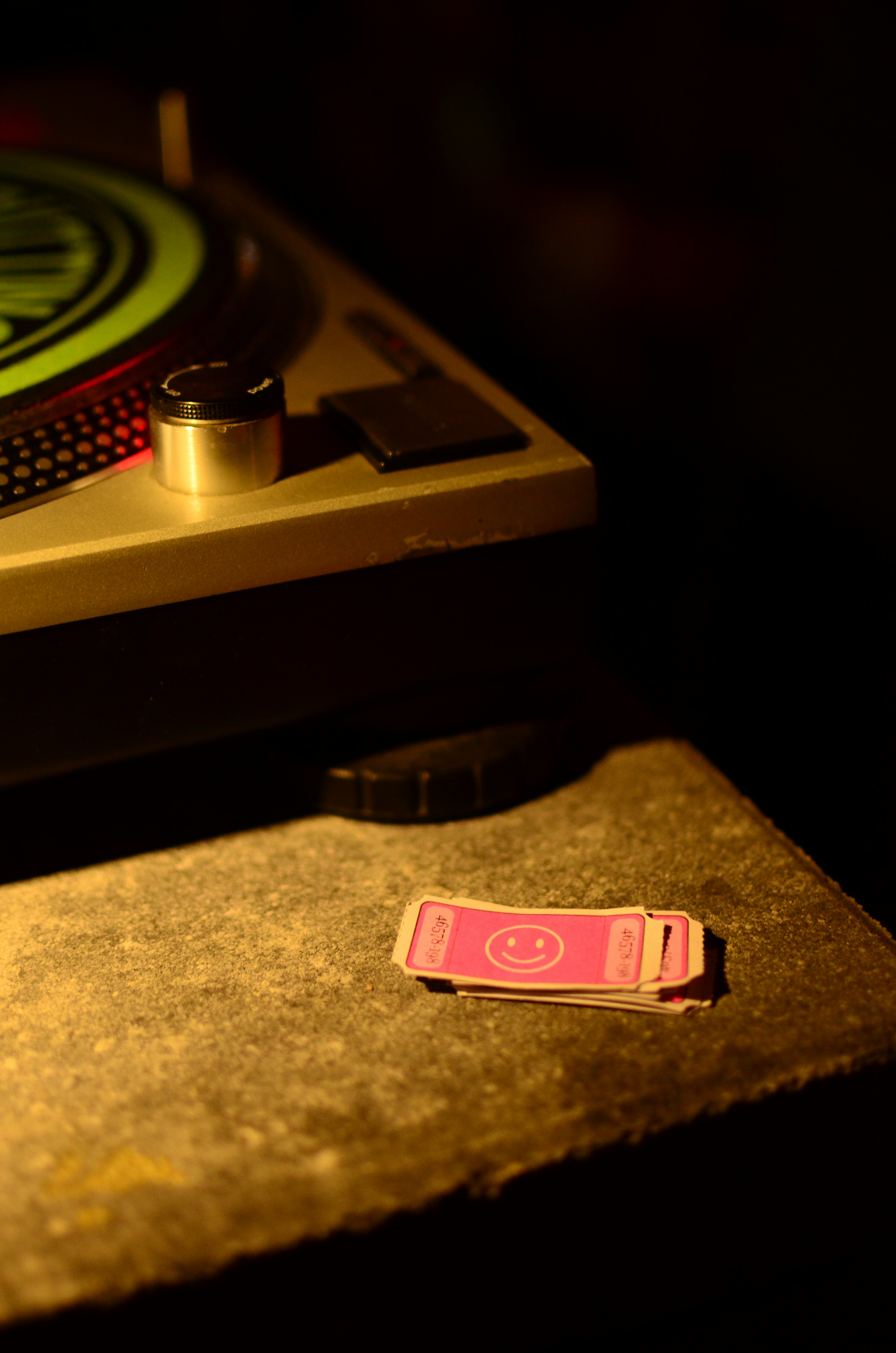 Stack of pink smiley tickets next to a turntable.
