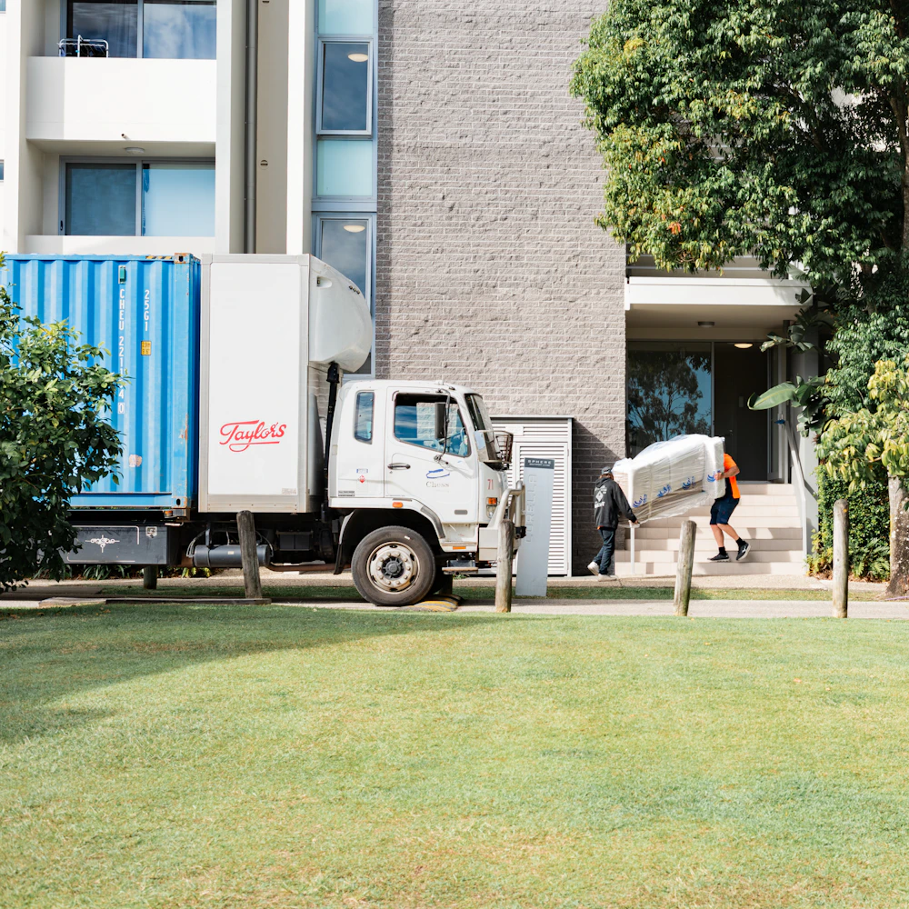 Moving crew unloading furniture from a moving truck outside an apartment building