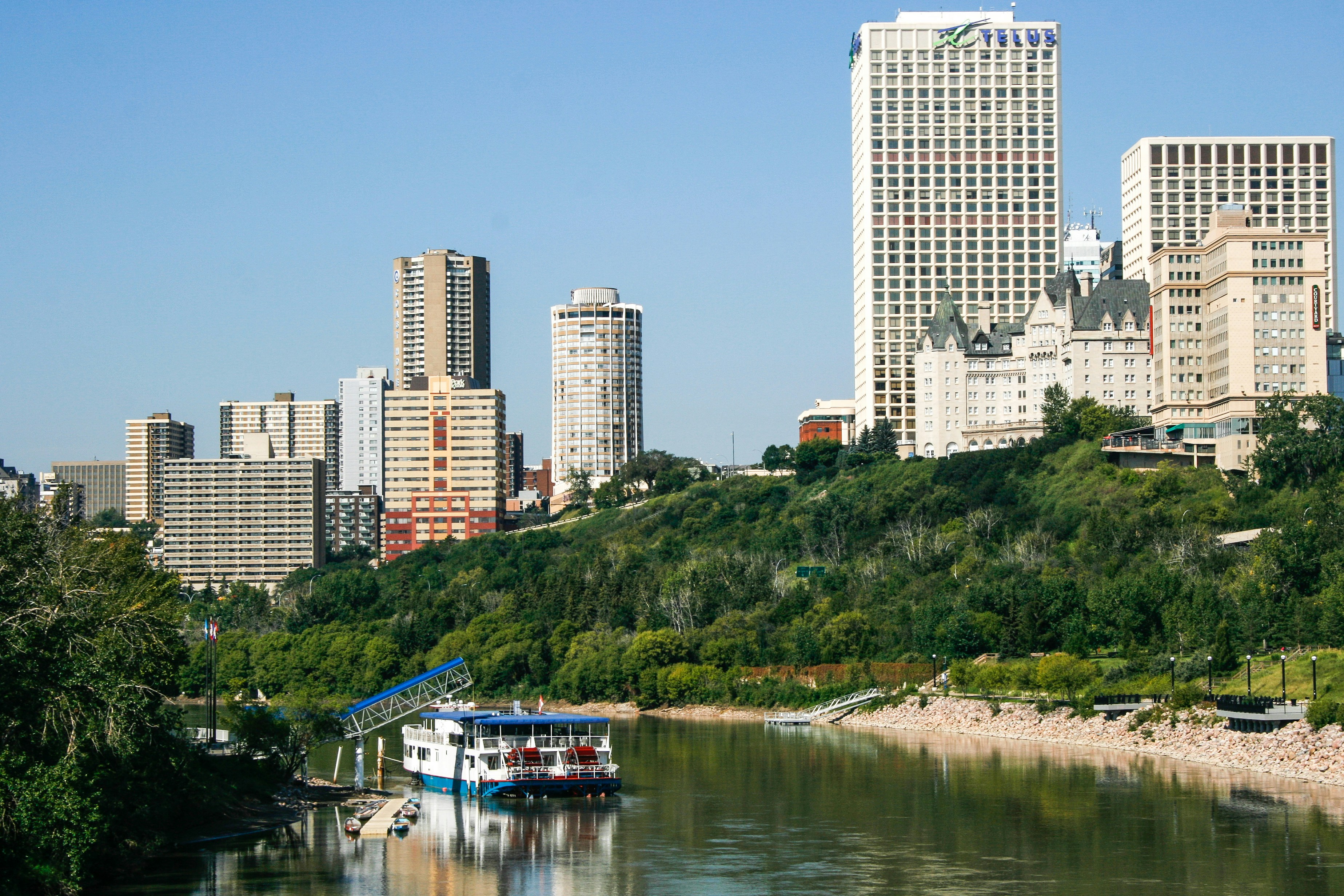 Horizonte urbano com um rio e um barco turístico.
