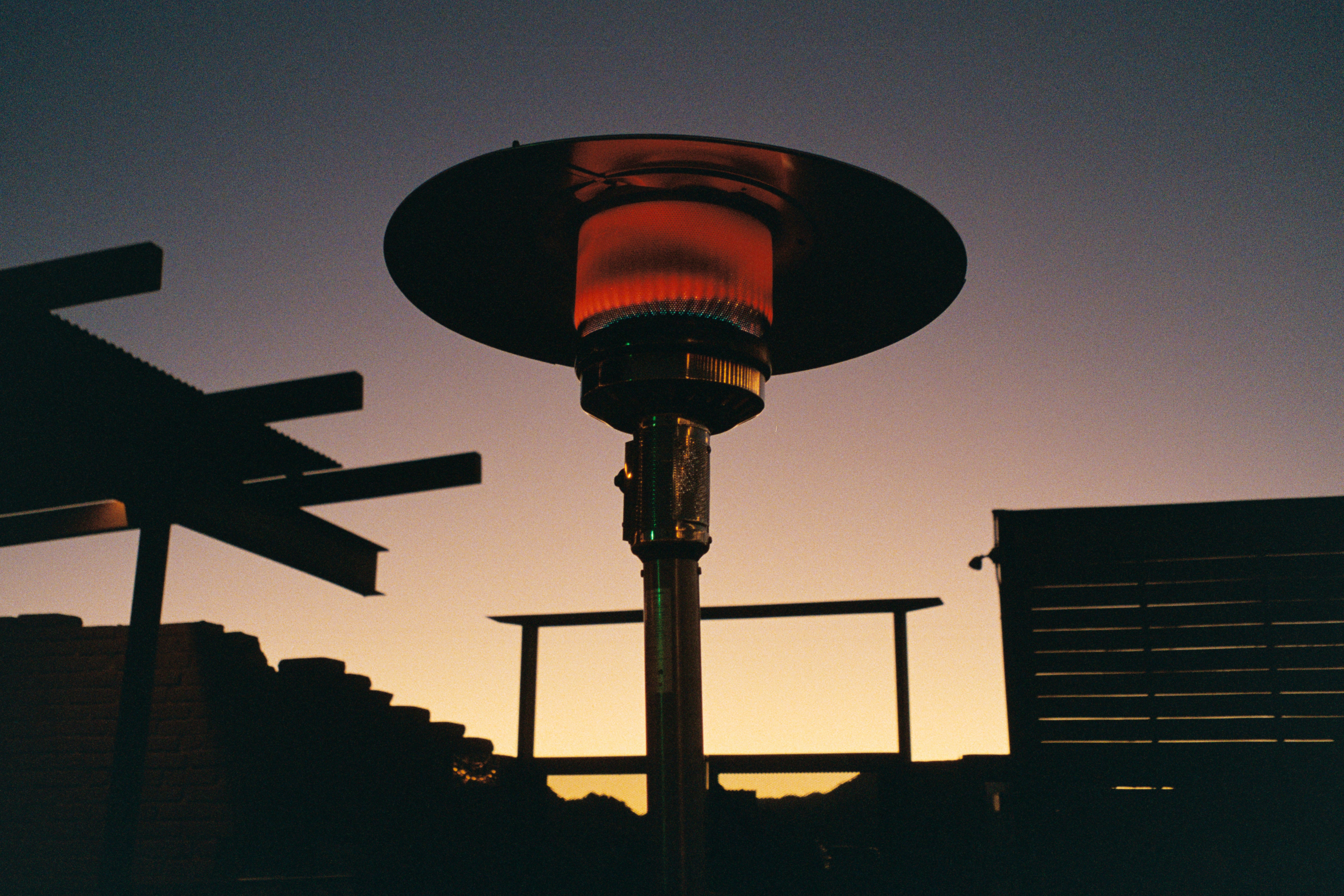 A patio heater glows orange against a sunset sky.