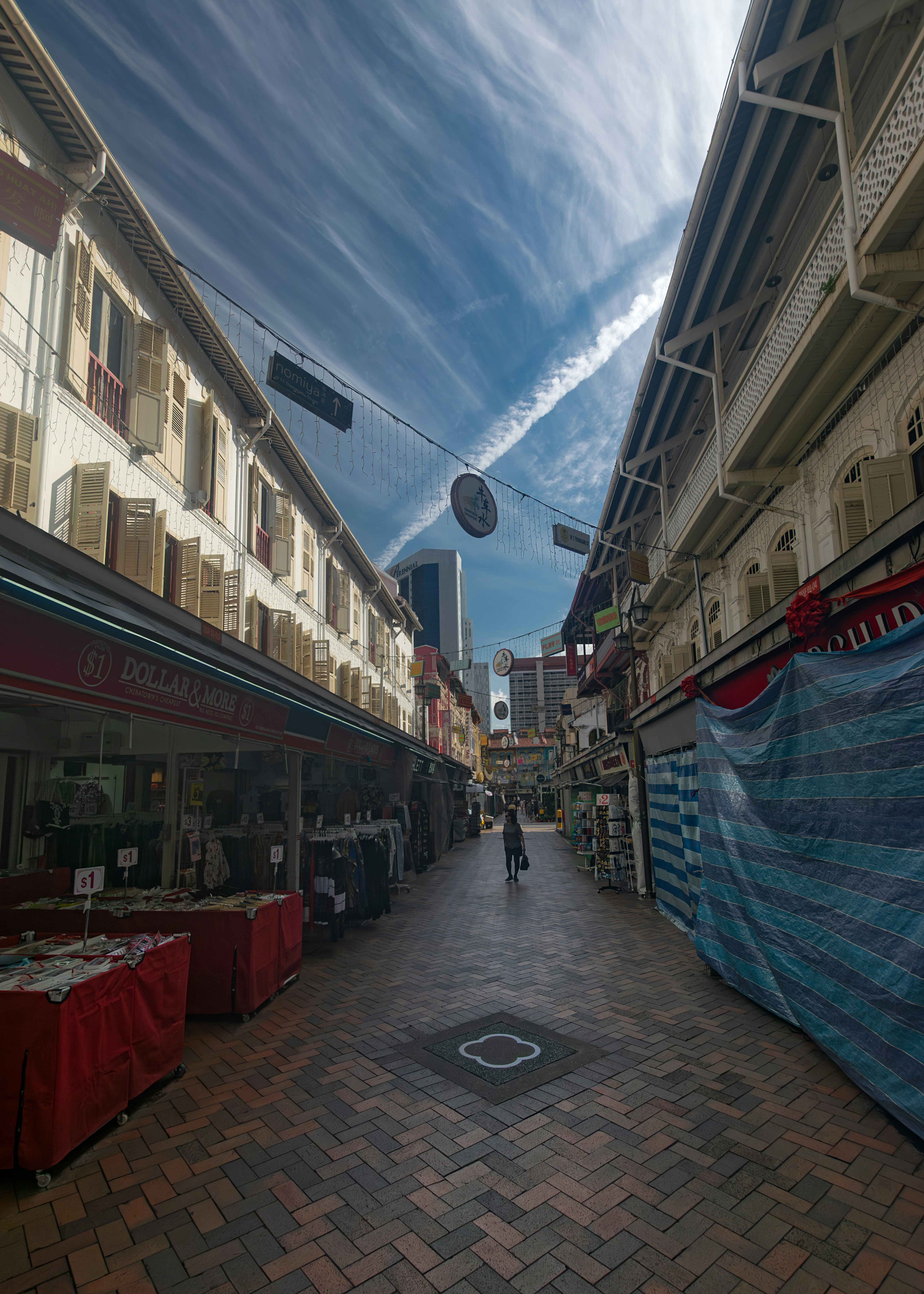 Narrow street with traditional shops under a unique sky.