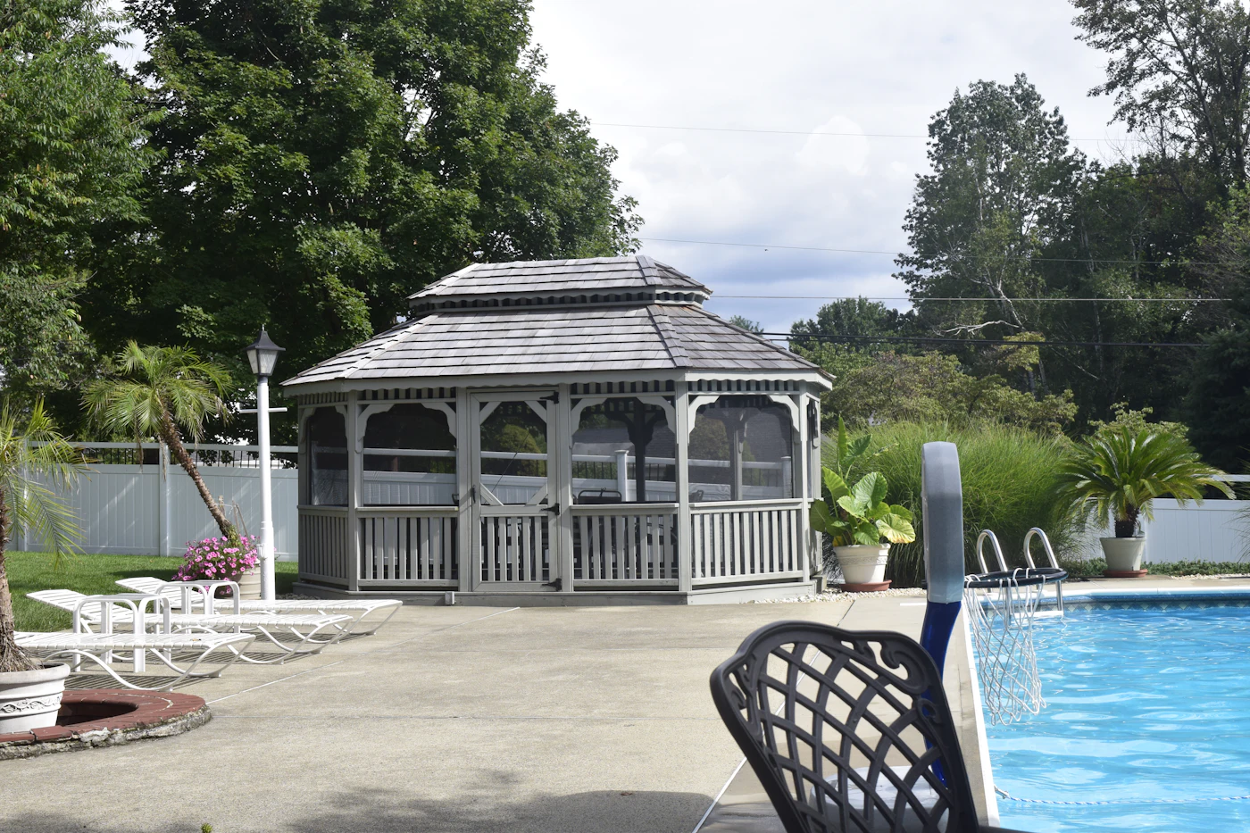 Custom backyard swimming pool beside a gazebo and patio