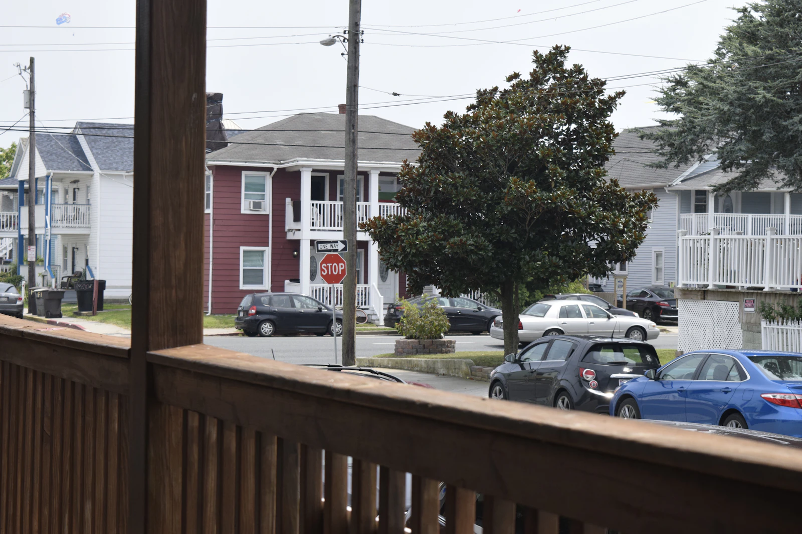 View from inside a home toward a residential street lined with parked cars and a stop sign, the kind of busy street our La Verne glass shop quiets for homeowners in Glendora, California