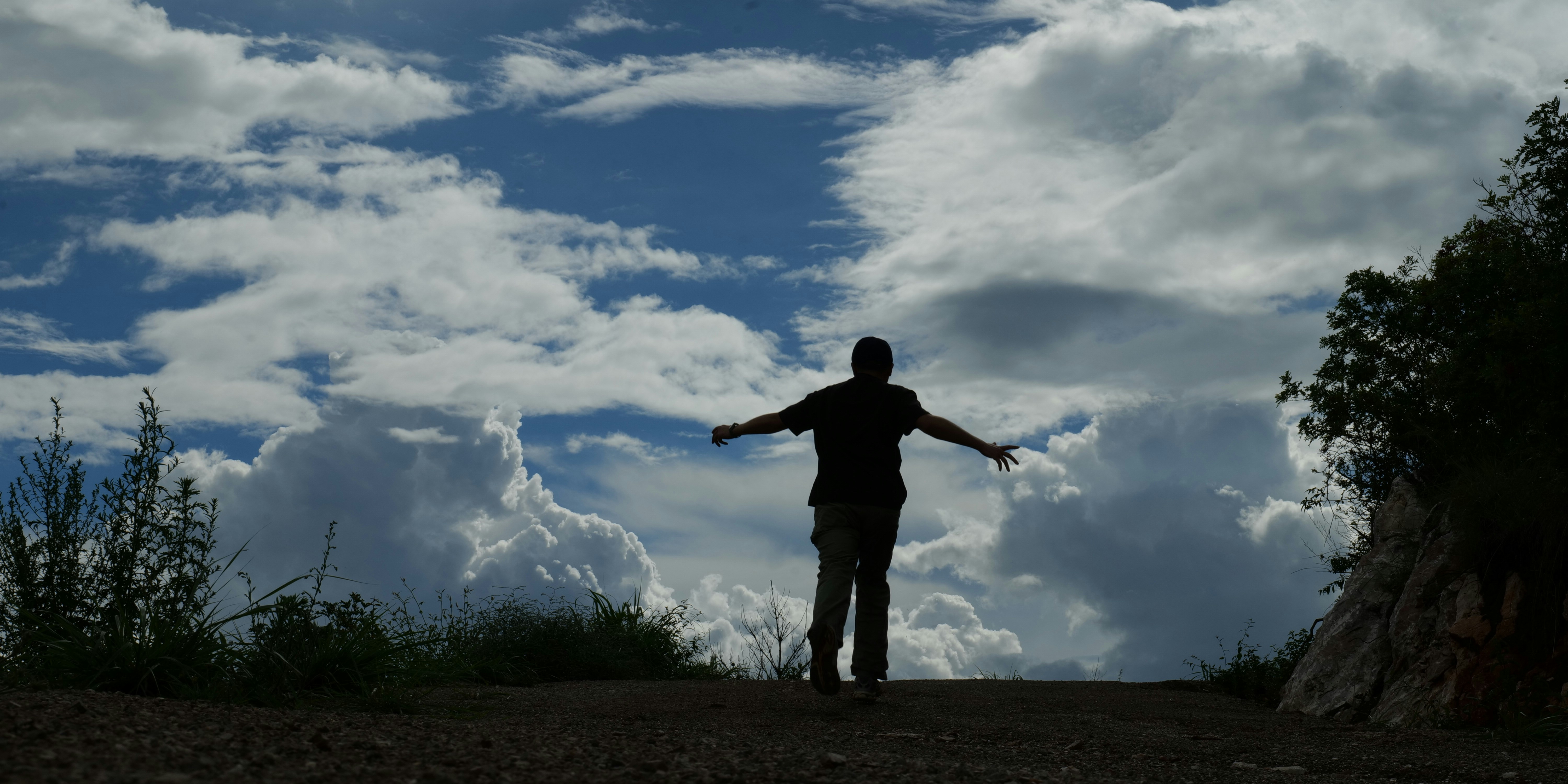 Person silhouetted against a vast sky with dramatic clouds.