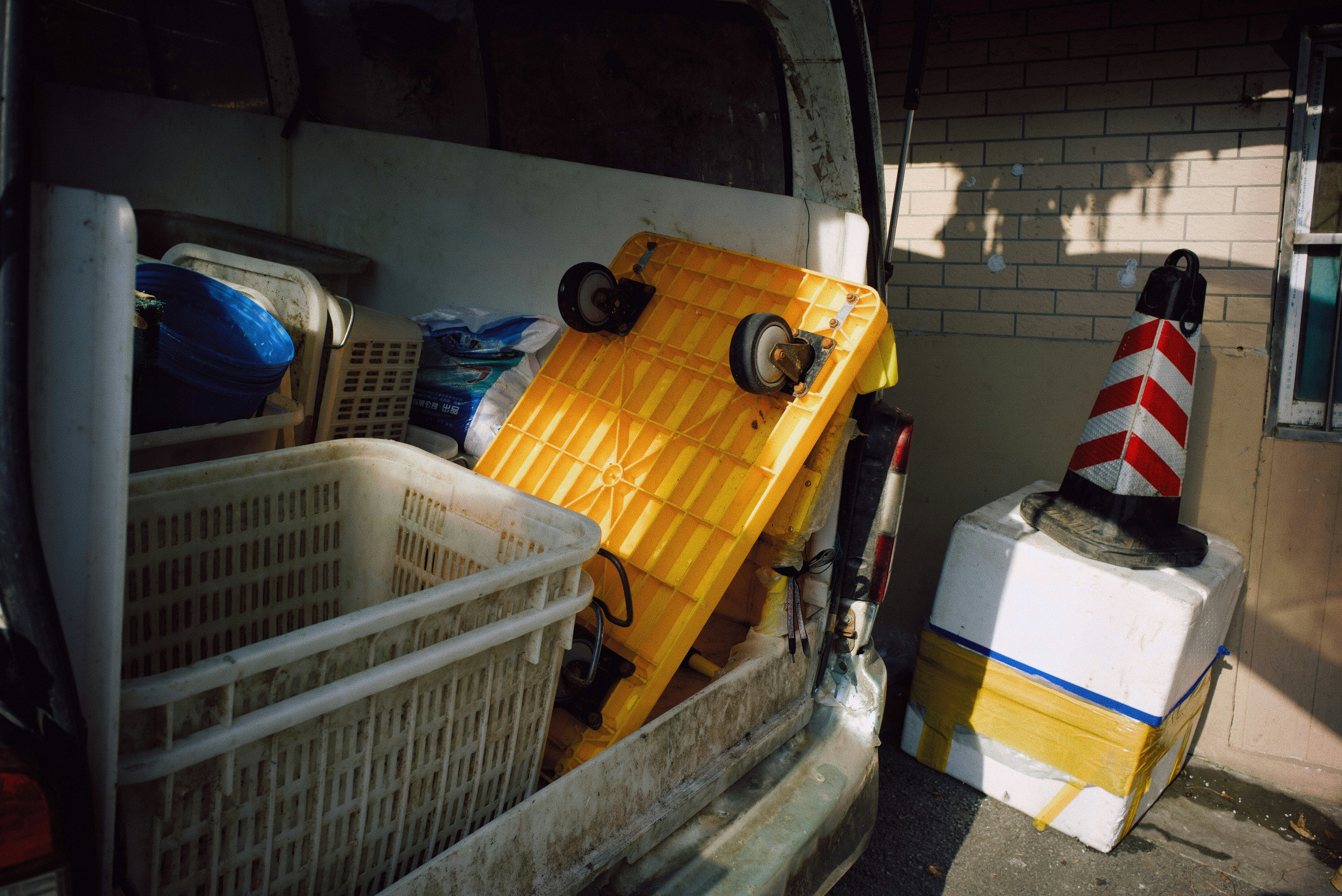 Open van with baskets, yellow cart, and traffic cone outside