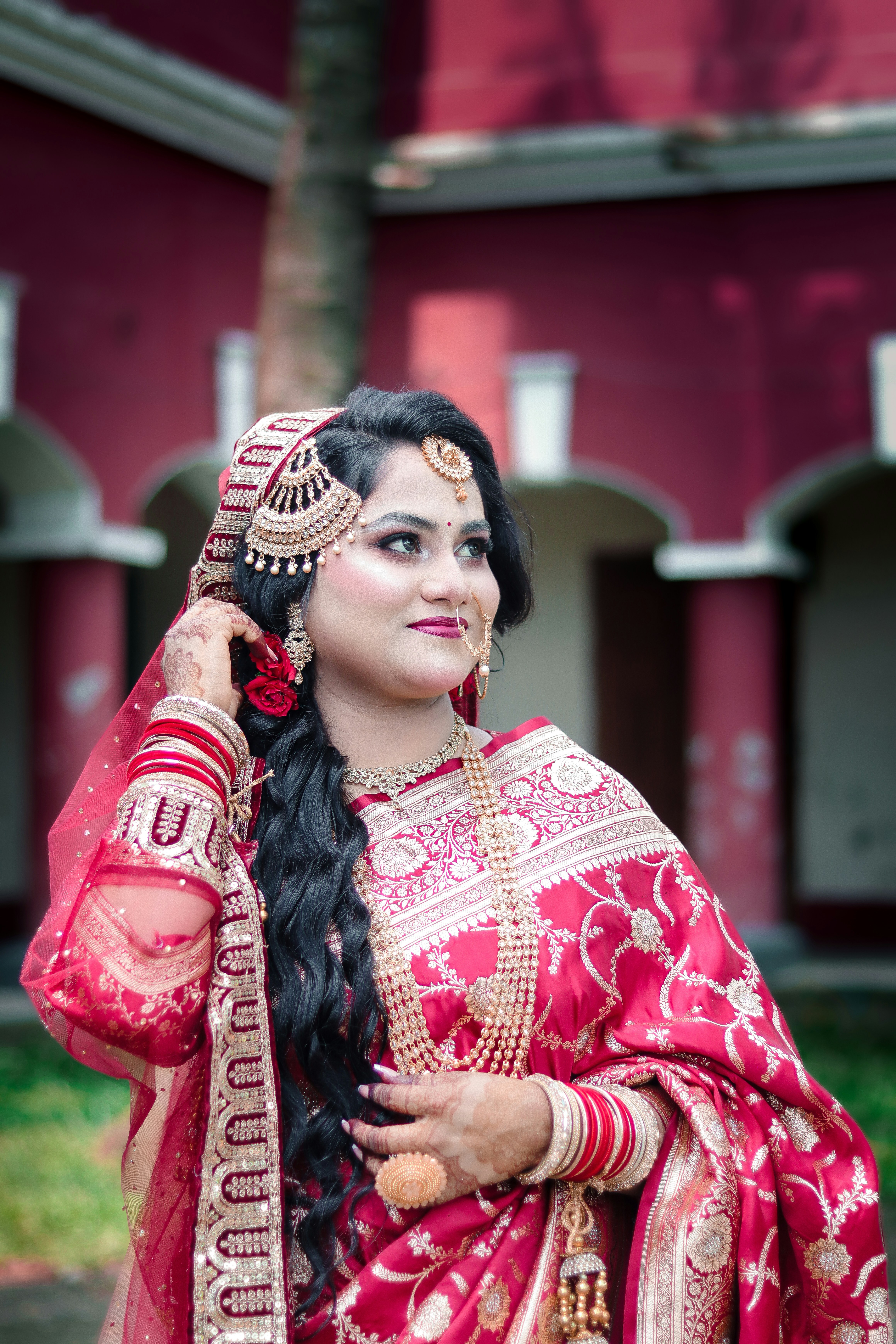 A beautiful woman in traditional red bridal attire and jewelry.