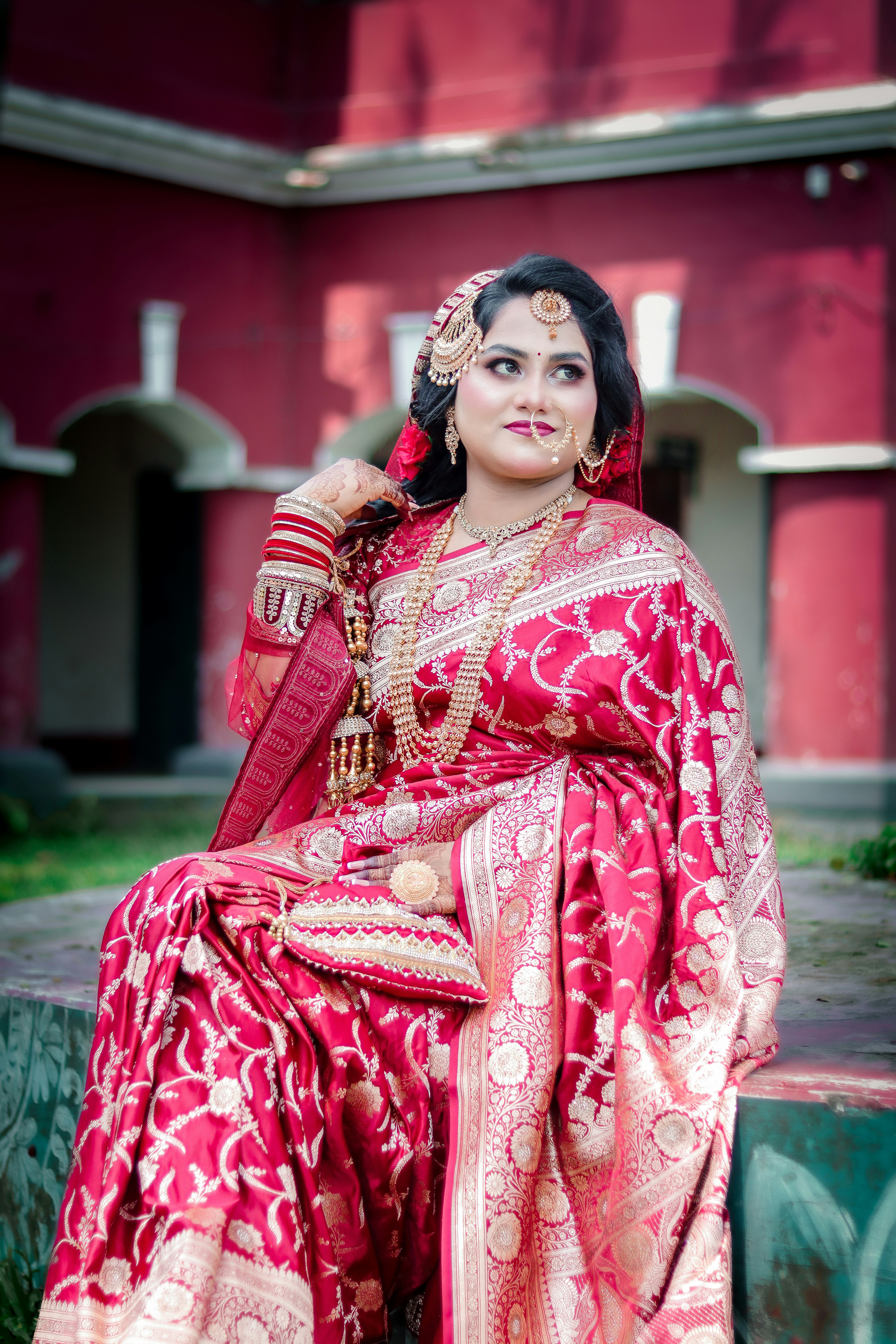 A woman in a vibrant red and gold traditional saree.