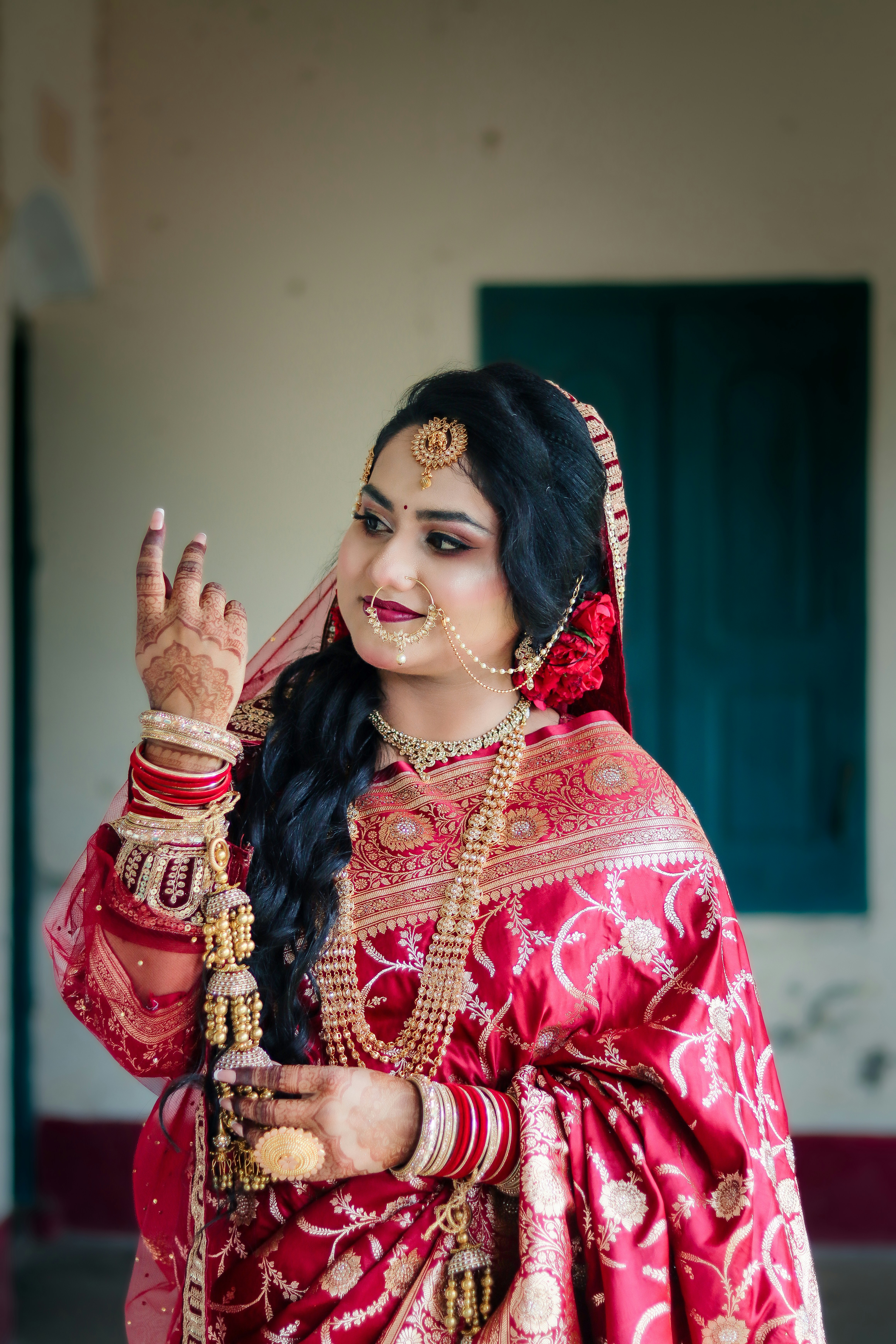 A beautiful bride in traditional red attire and gold jewelry.