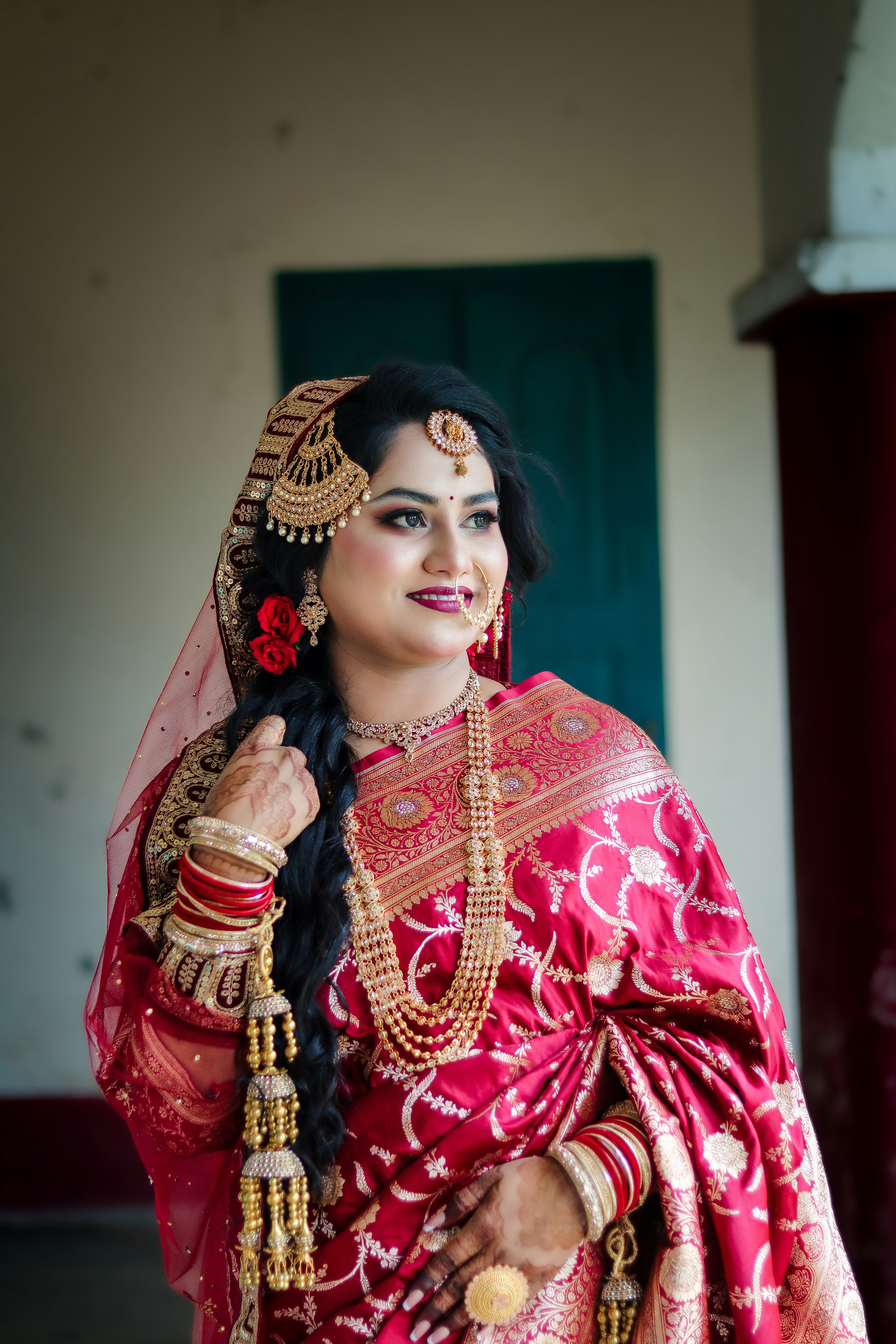 Indian bride wearing traditional red saree and intricate gold jewelry.