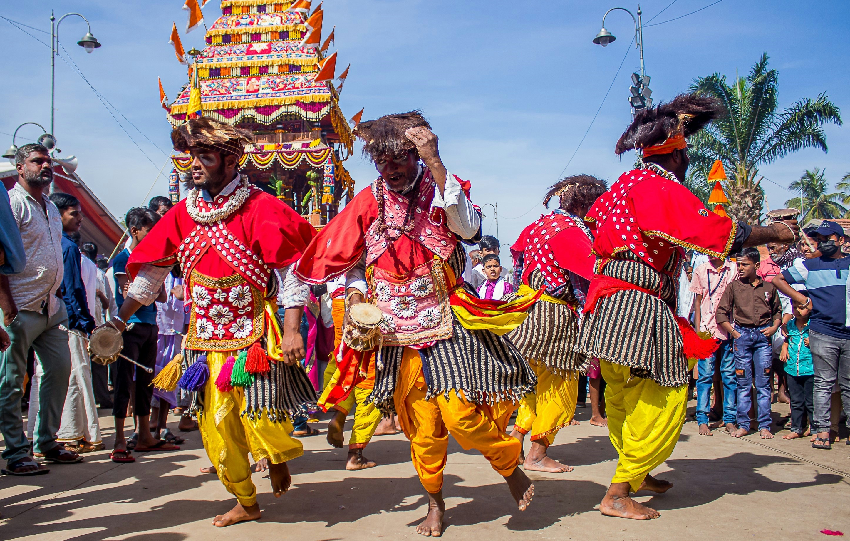 Men in colorful traditional attire dancing at an outdoor festival.