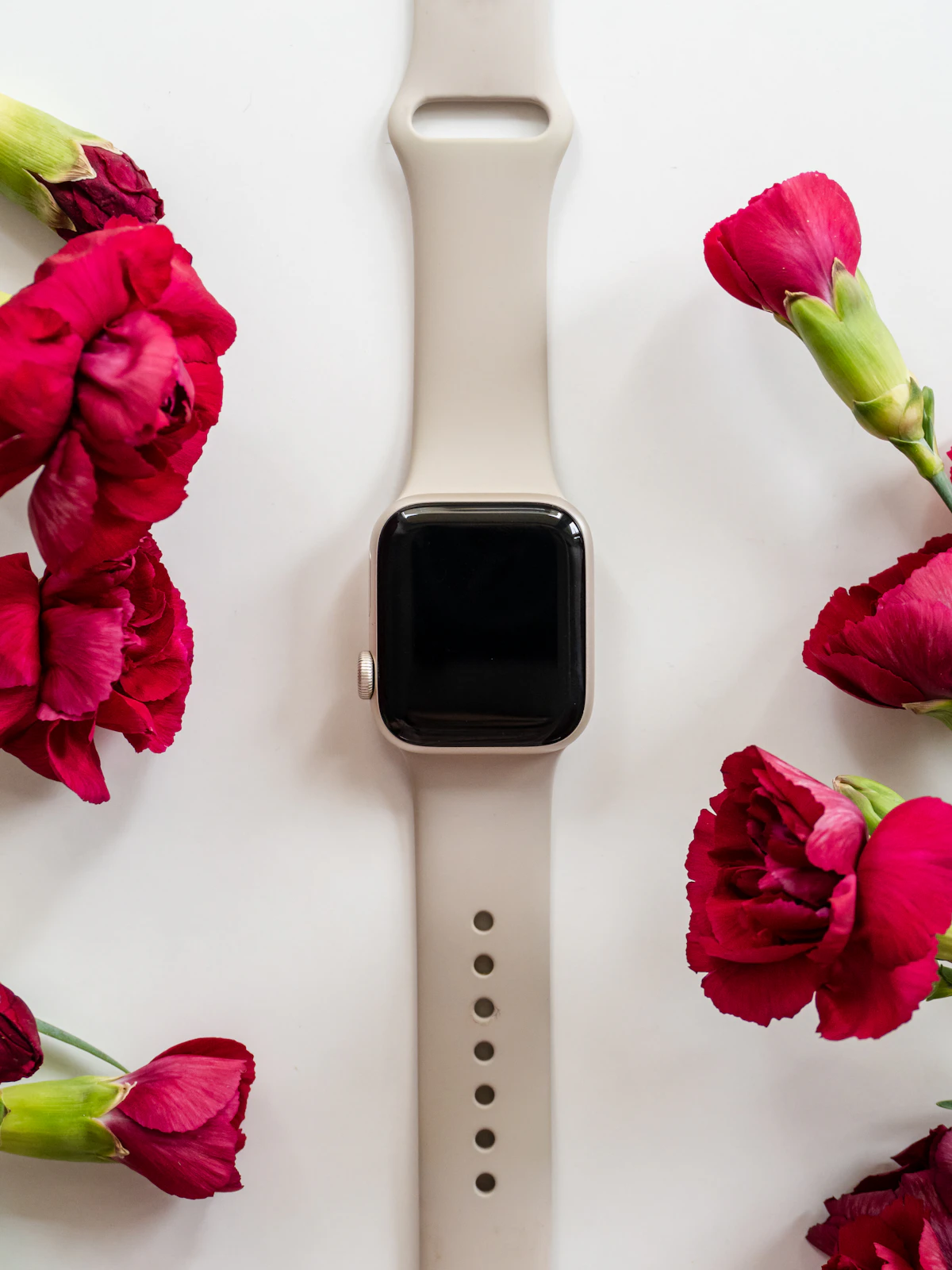 Styled product photo of a smartwatch with red carnations