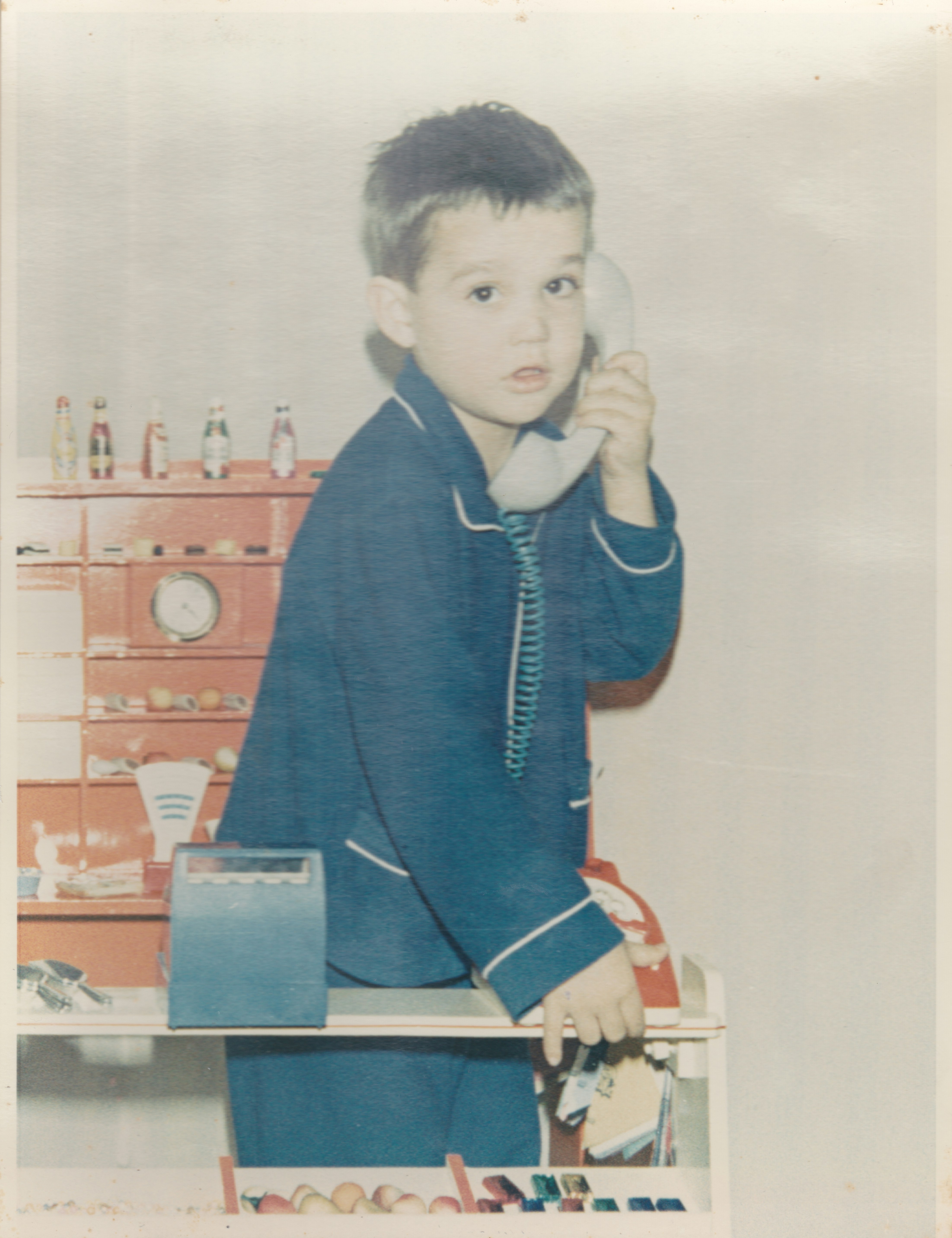 Young boy in pajamas playing with a toy phone.