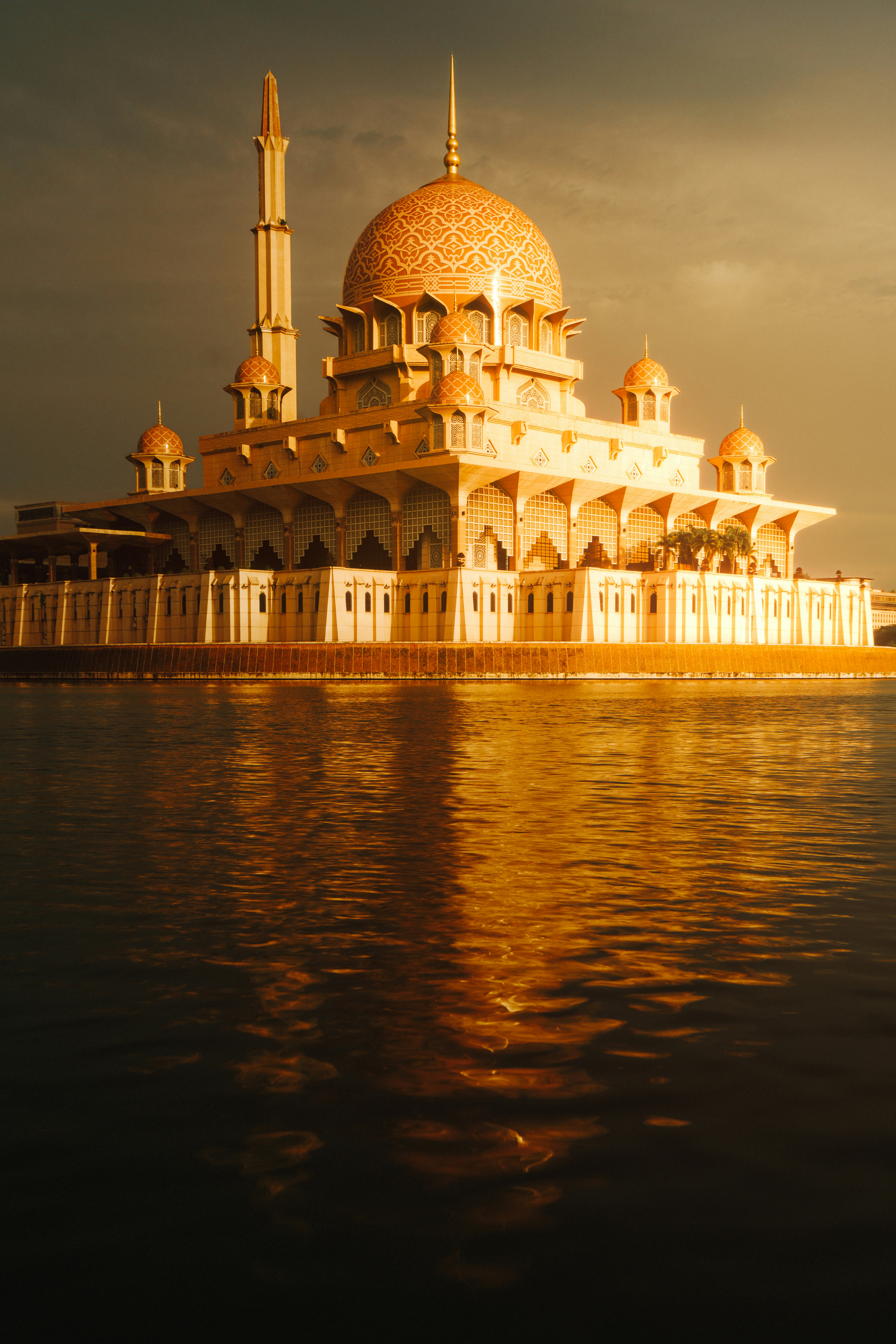 Ornate mosque with golden dome reflecting in water