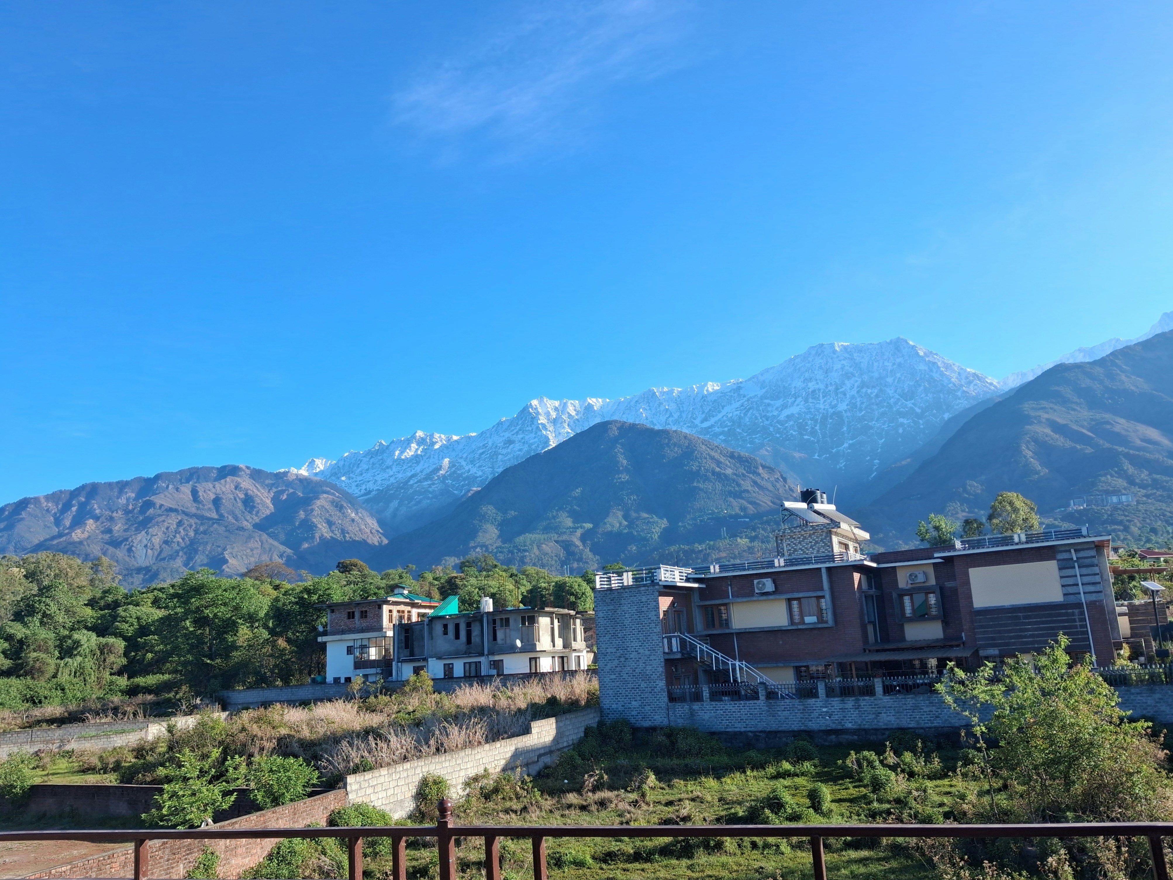 Snow-capped mountains behind buildings under a clear blue sky.