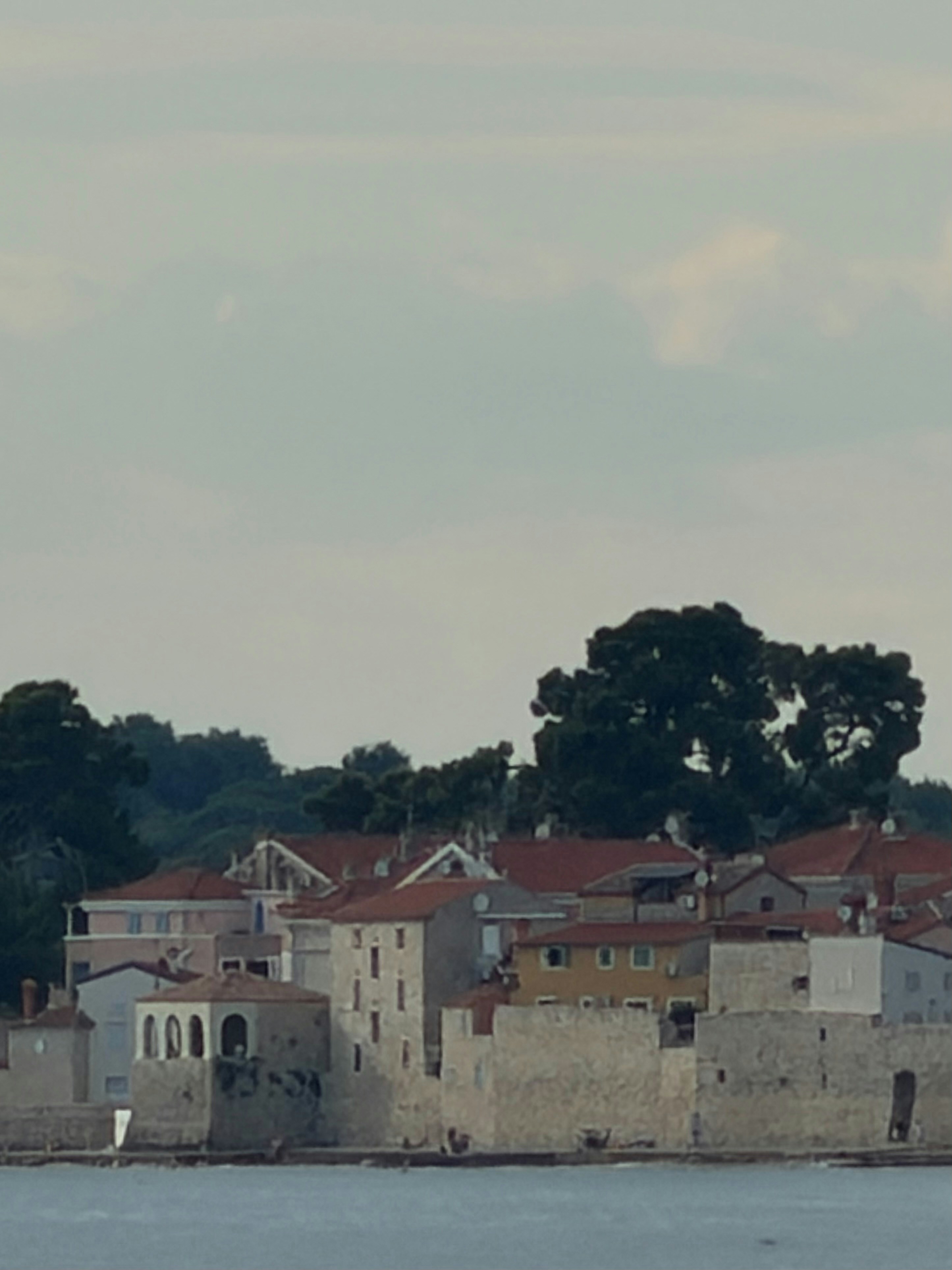 Old stone town with red roofs by the water.