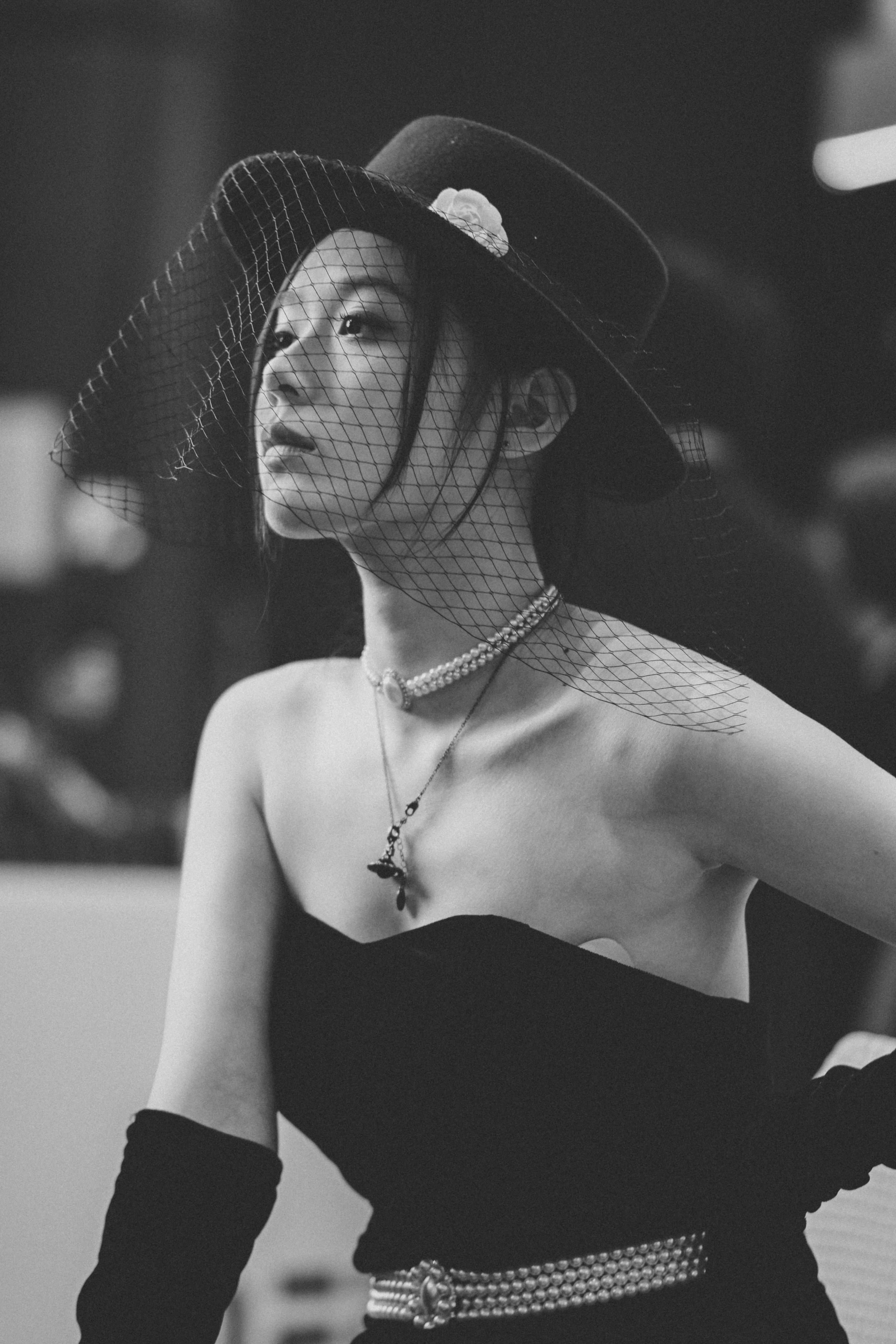 Donna alla moda in abito nero e cappello velato.