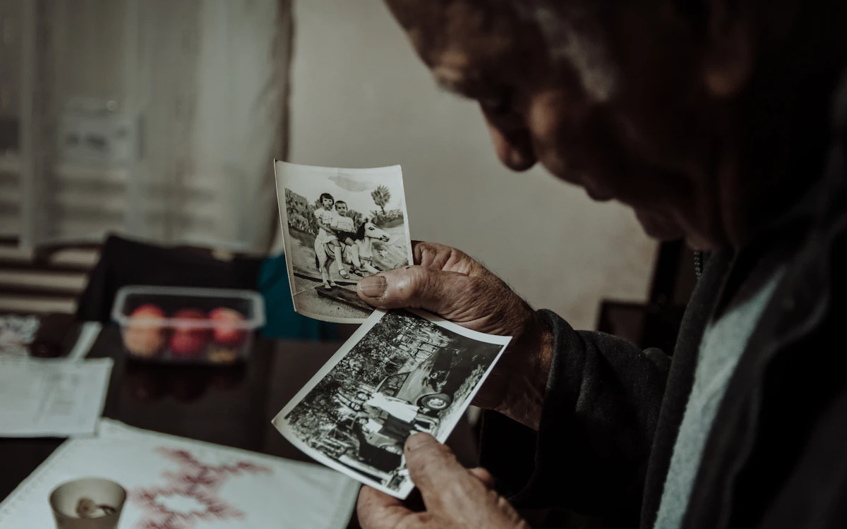 Seorang lansia memeriksa foto hitam putih lama.