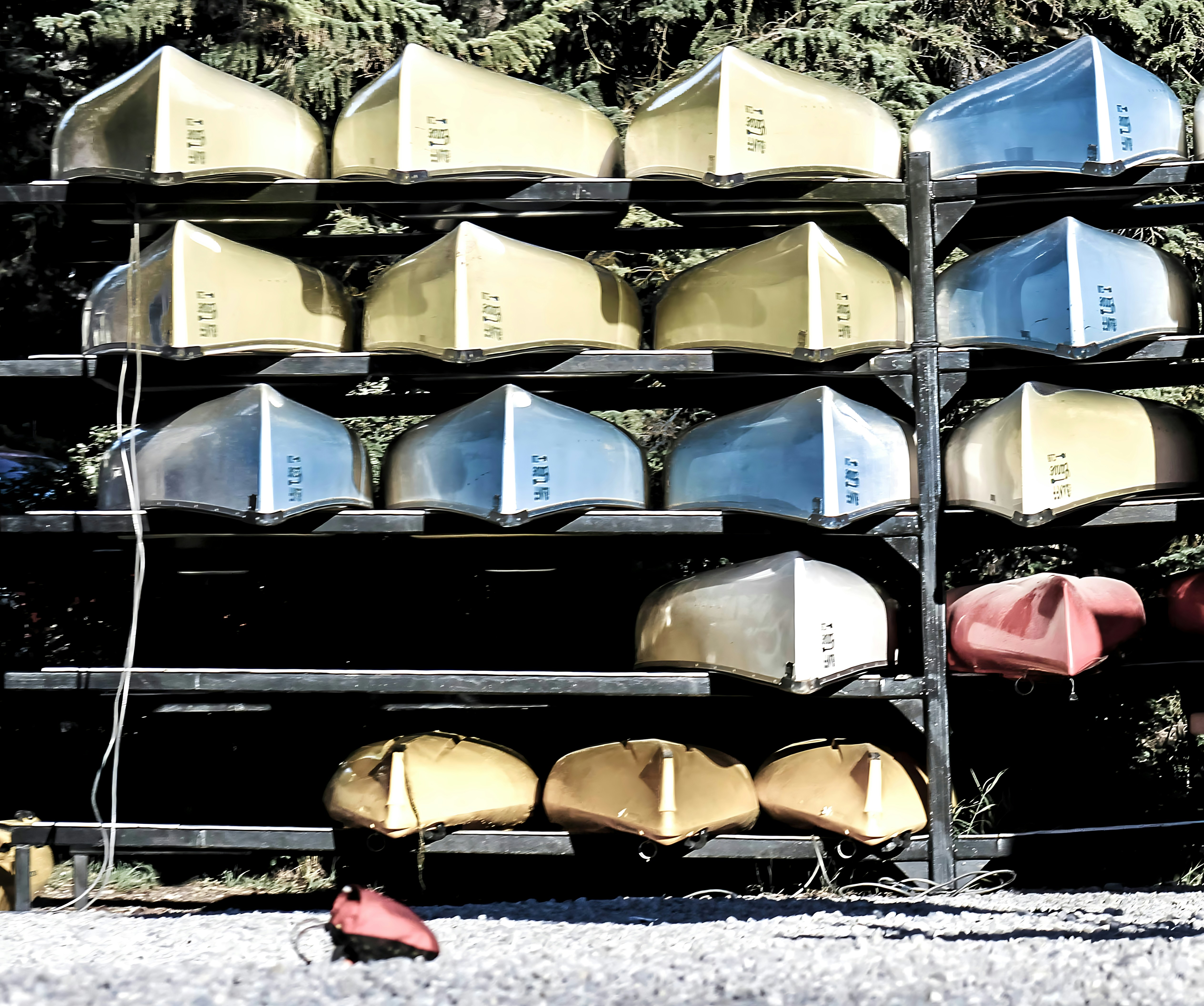 Canoas coloridas apiladas sobre estantes metálicos al sol