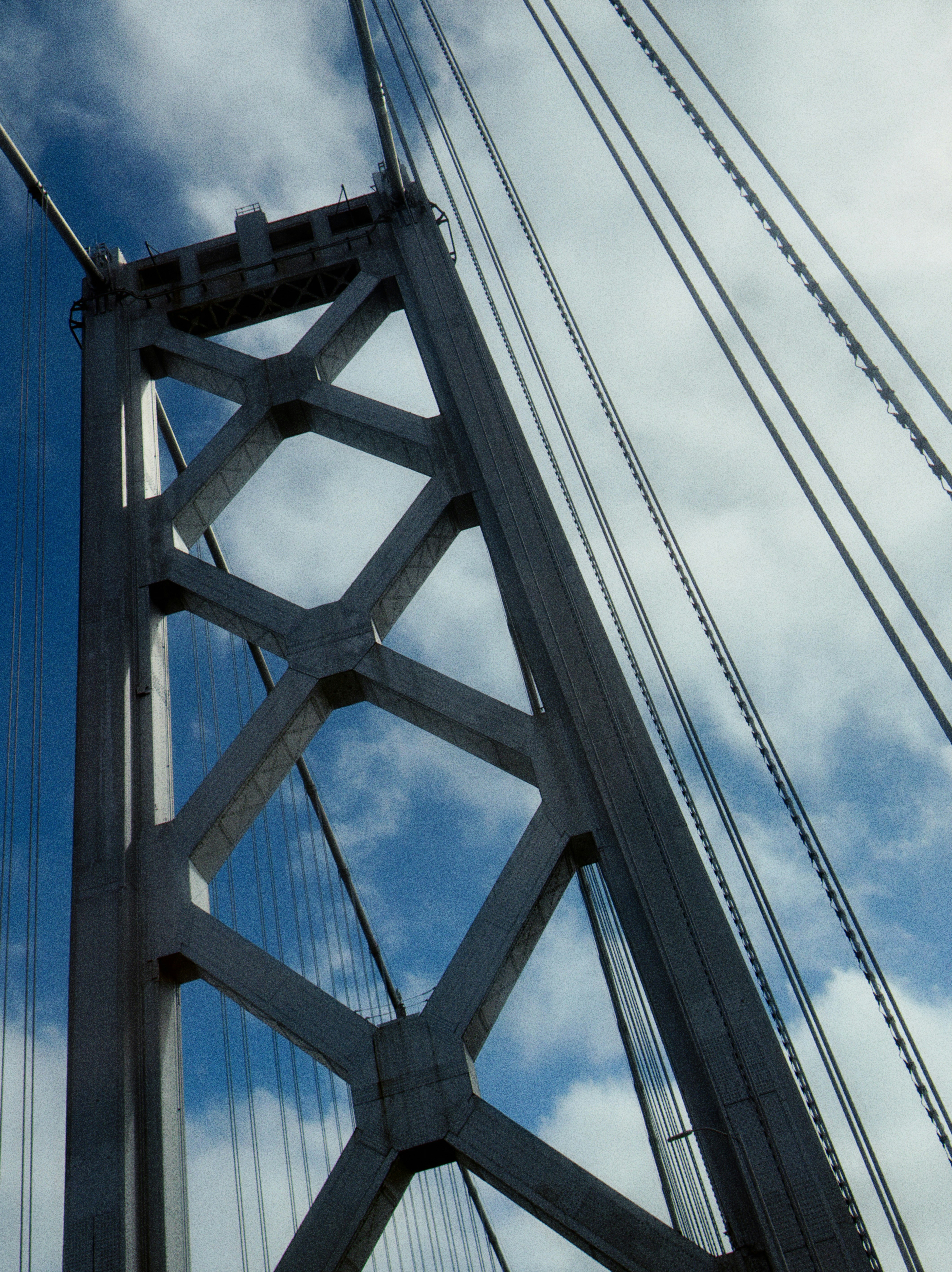 Bridge tower and cables against a cloudy sky