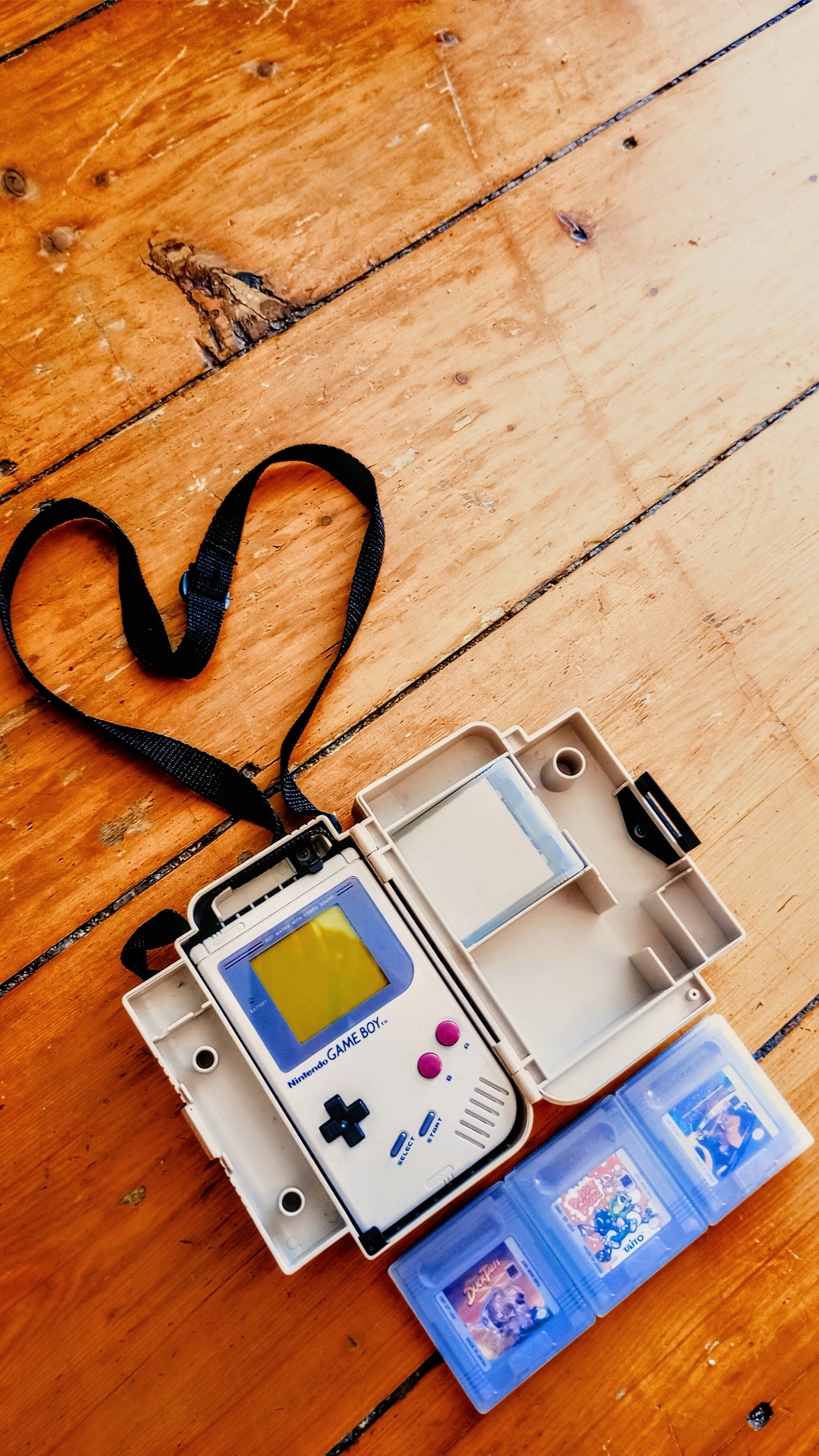 Vintage nintendo game boy with games and case on wood.