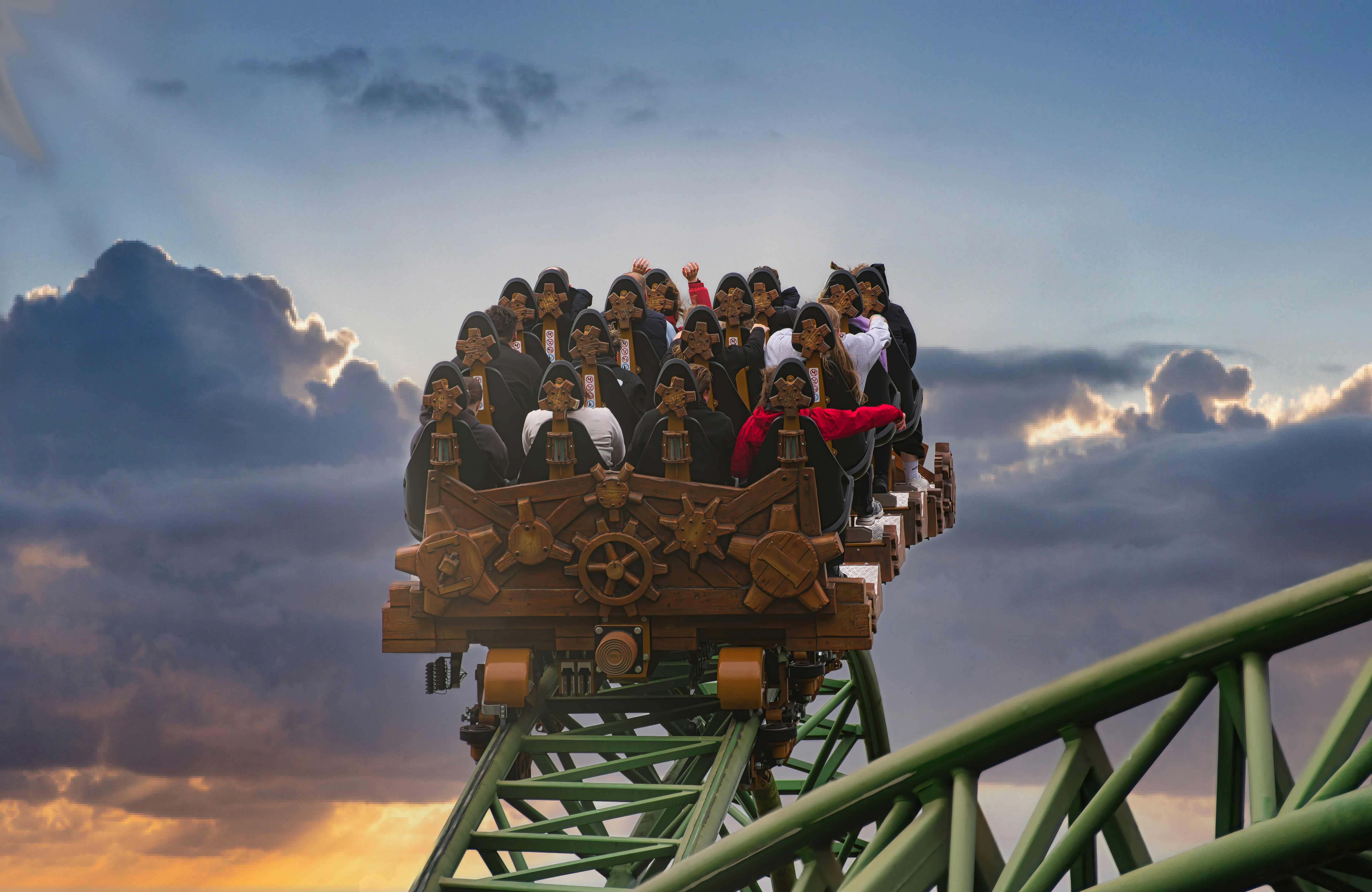 Rollercoaster full of excited people under a dramatic sky.
