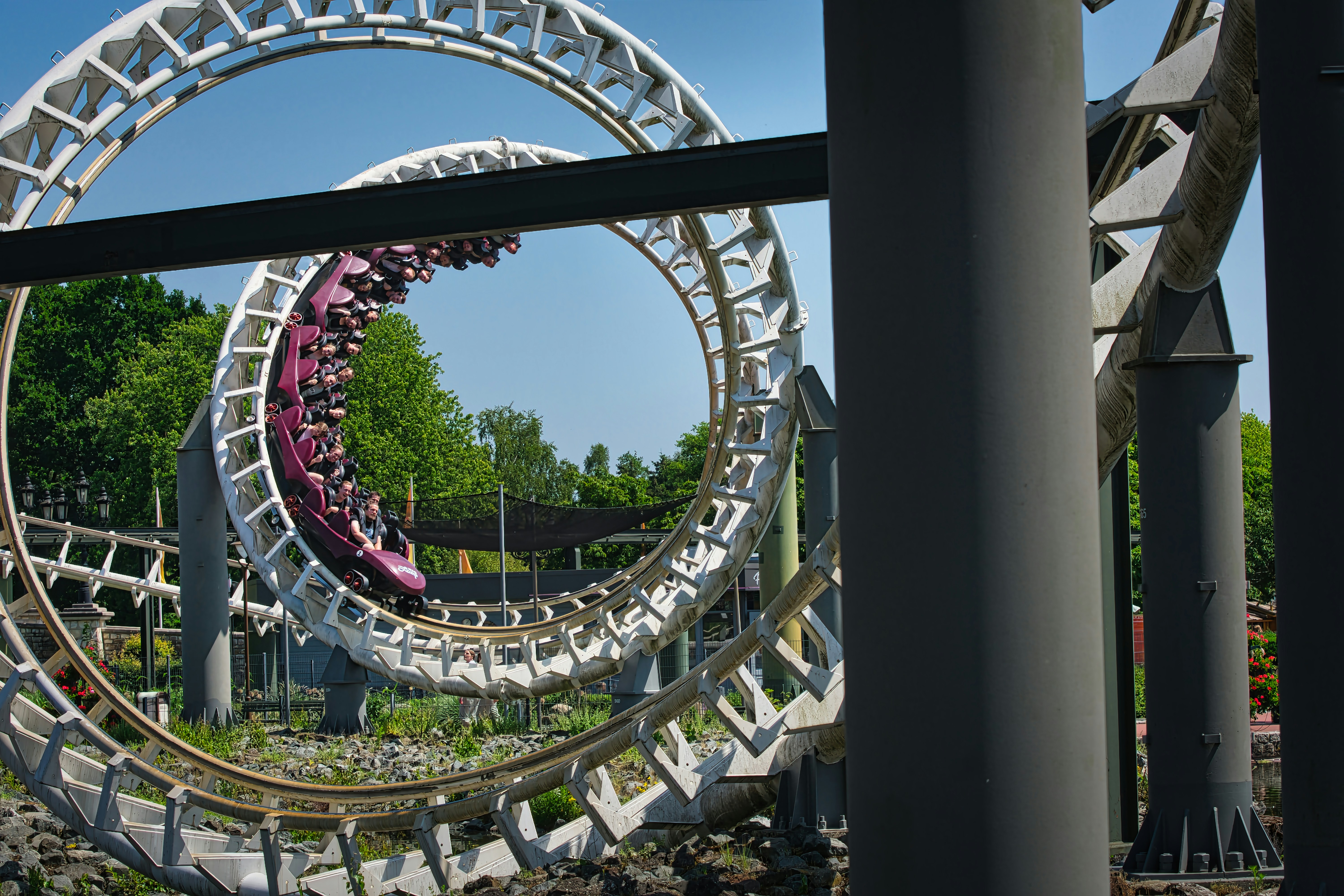 Rollercoaster train navigating multiple loops under a blue sky.