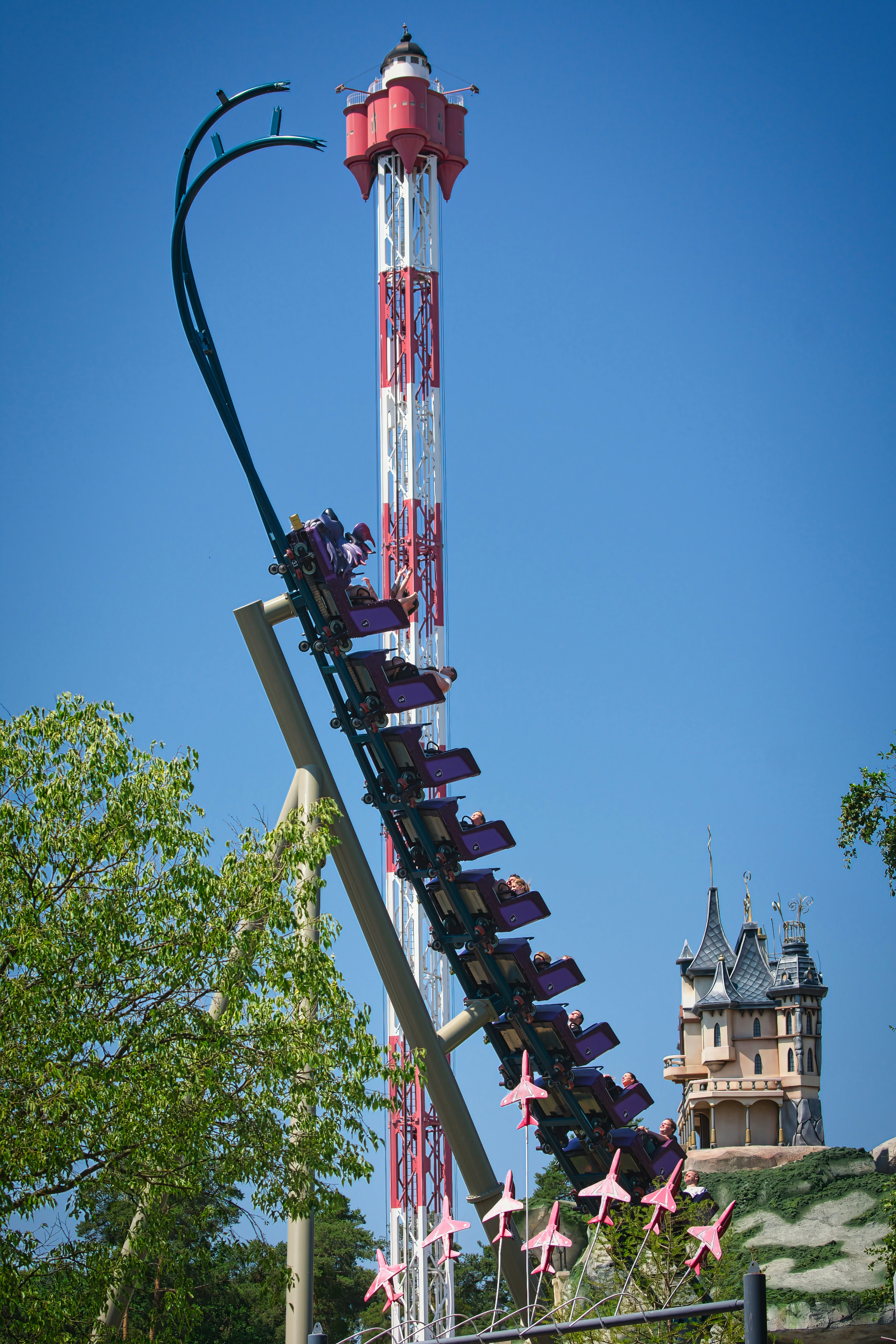 A thrilling roller coaster ascends a tall drop tower ride.