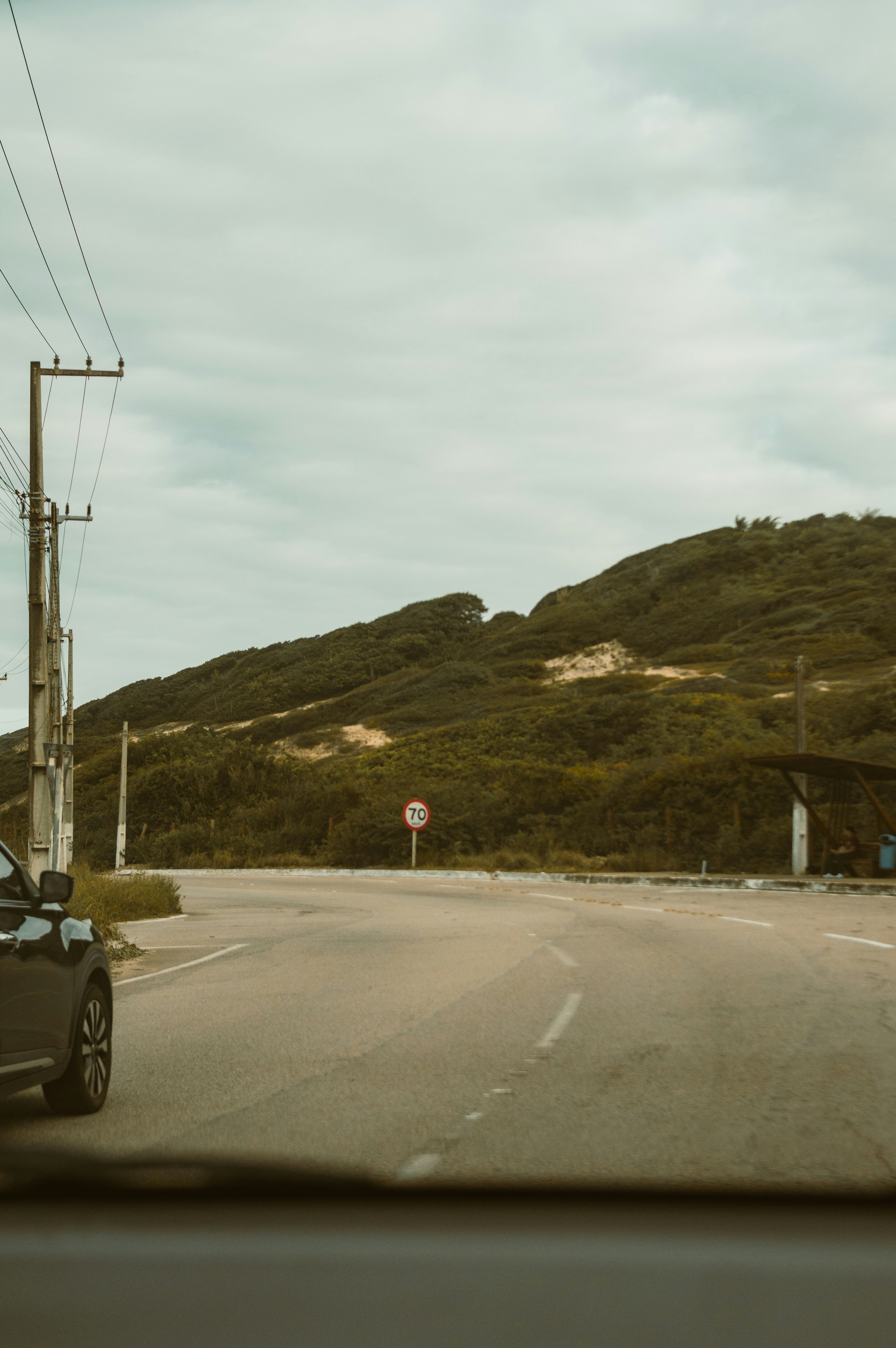 Driver performing driving stretch breaks beside a car during a long road trip