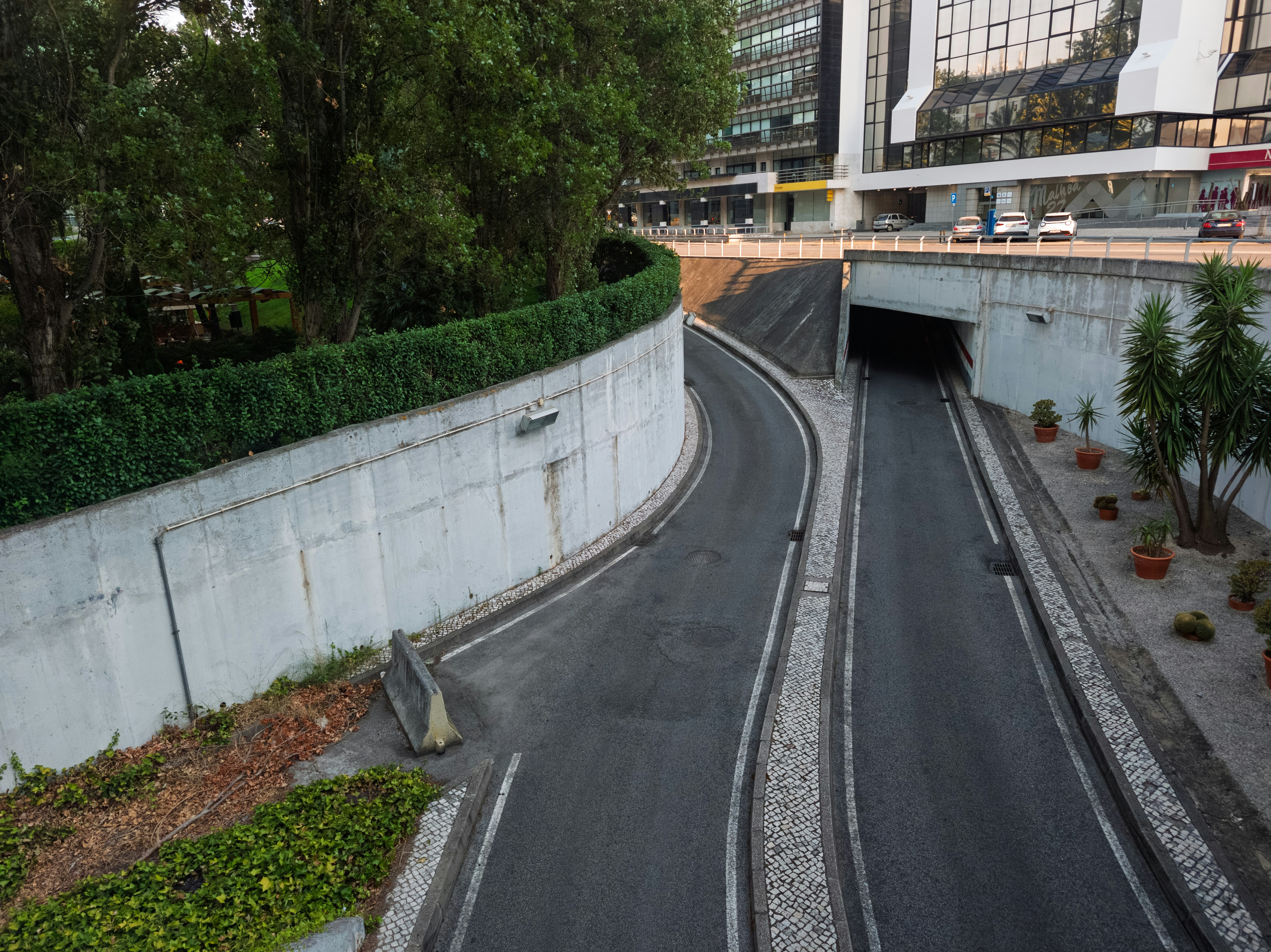 Curved road descends into a dark urban tunnel.