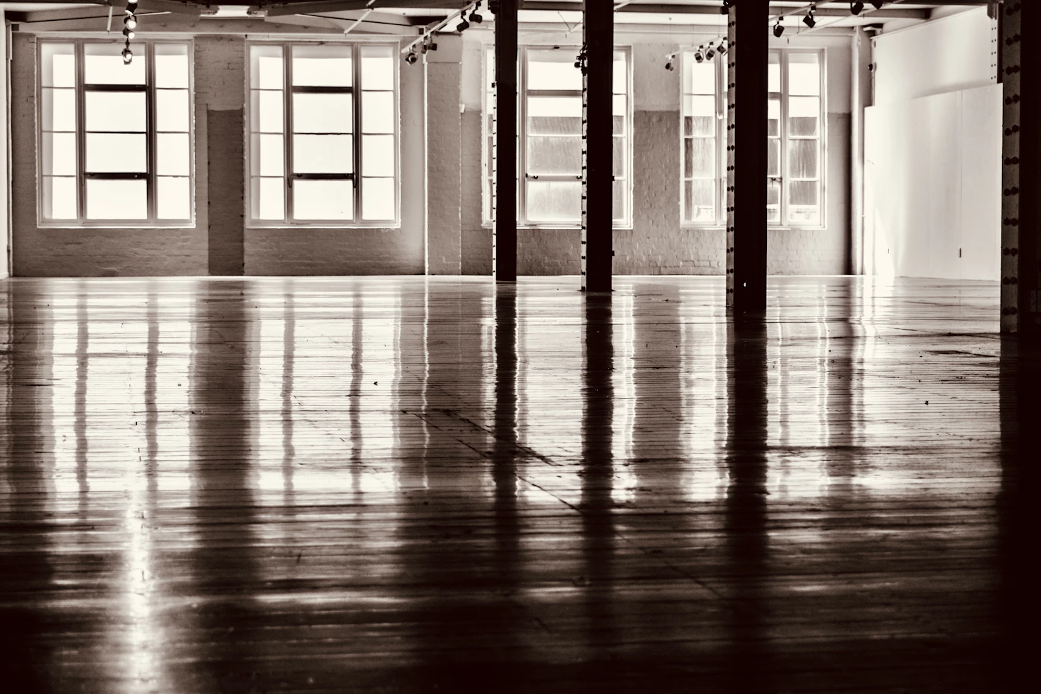 An empty first-floor hall, tall windows reflected the length of a worn timber floor